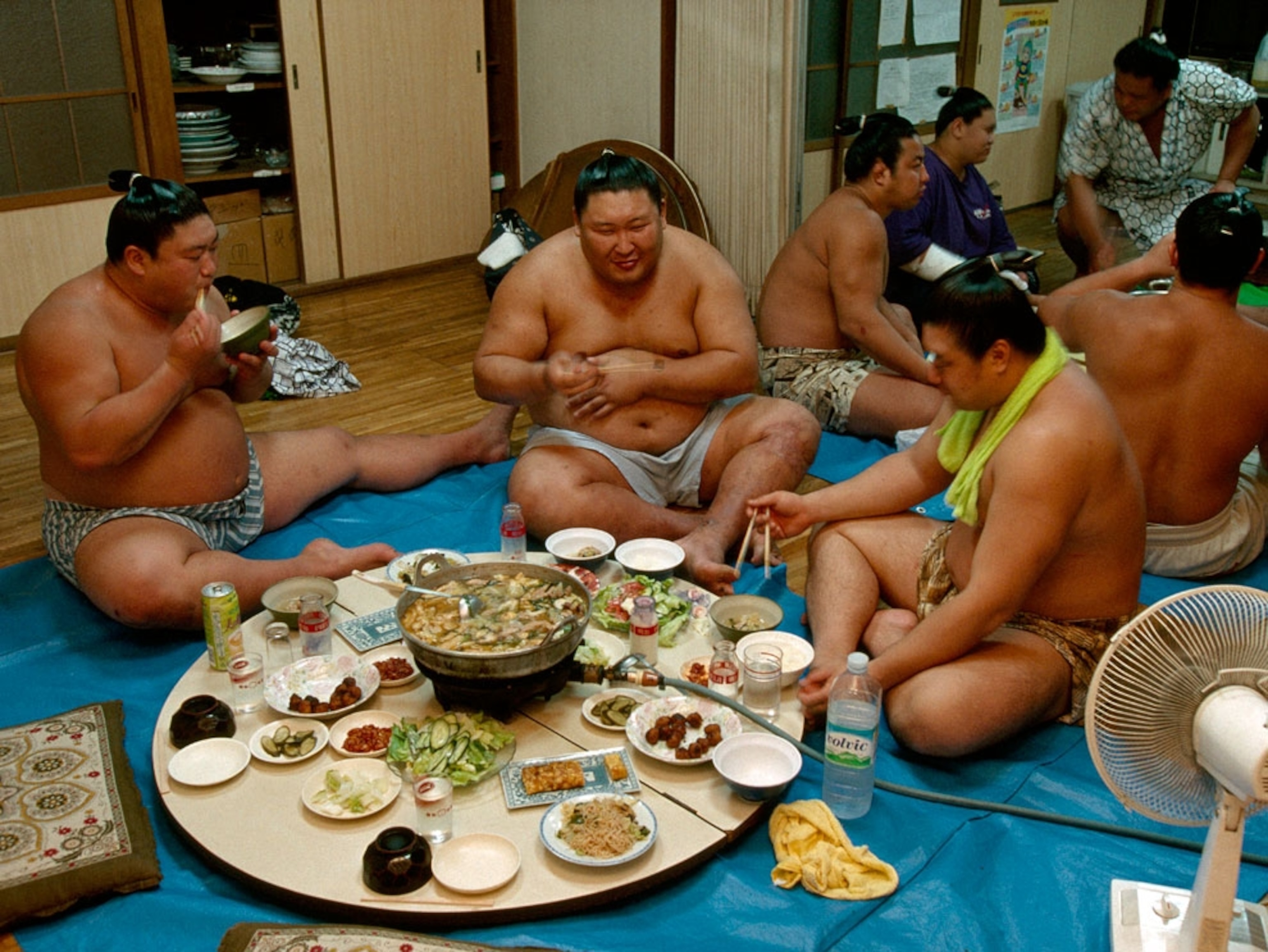Men sitting around tables of food, eating