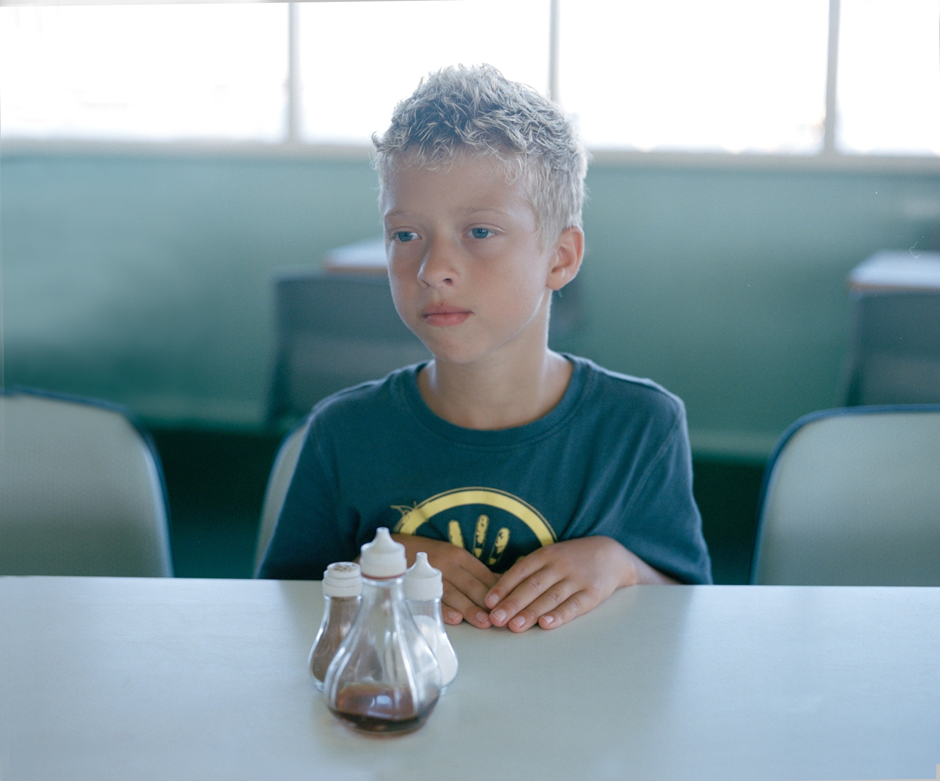 a boy sitting in front of salt shakers