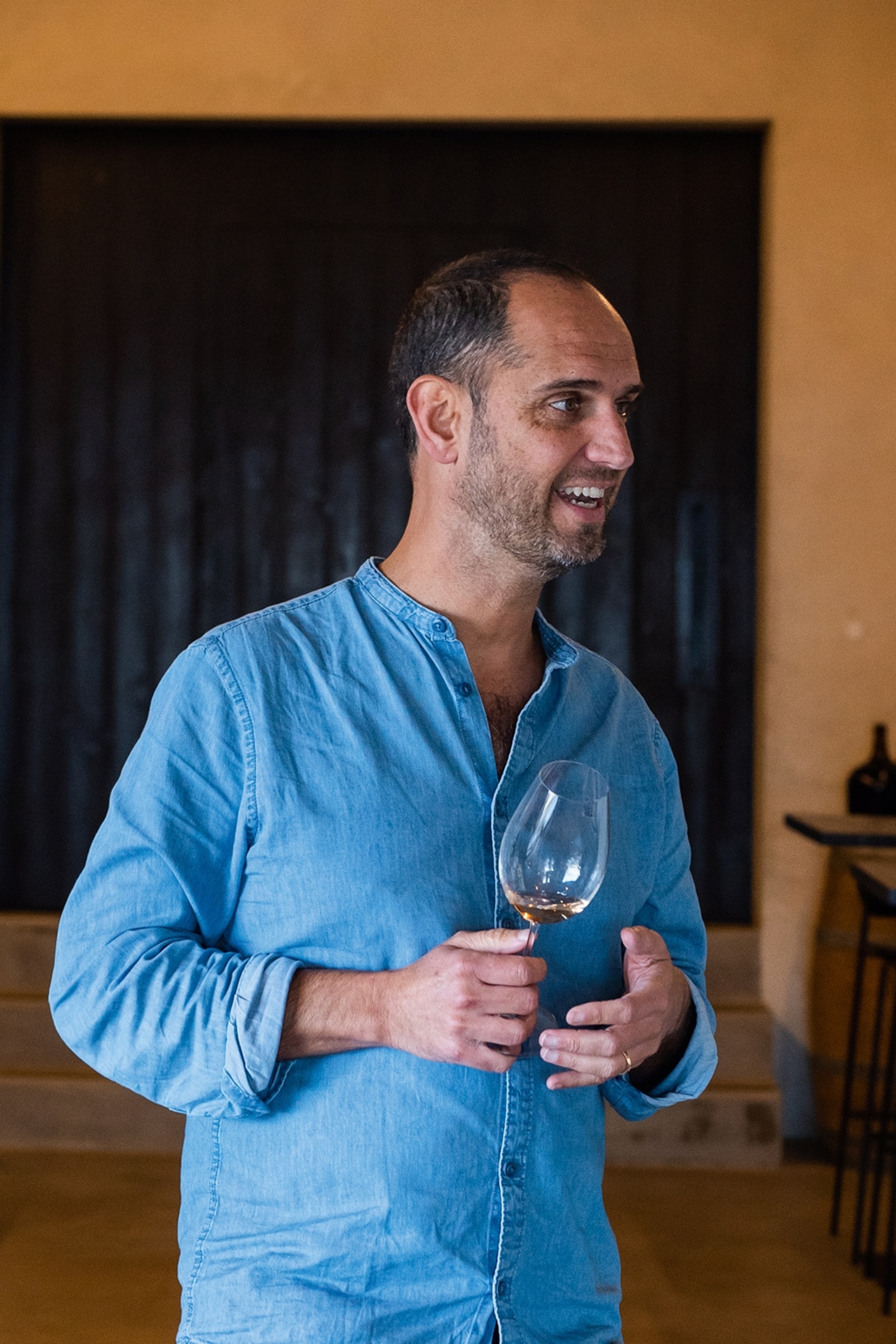 A local sommelier and winemaker caught mid-speech with a glass of wine in one hand.
