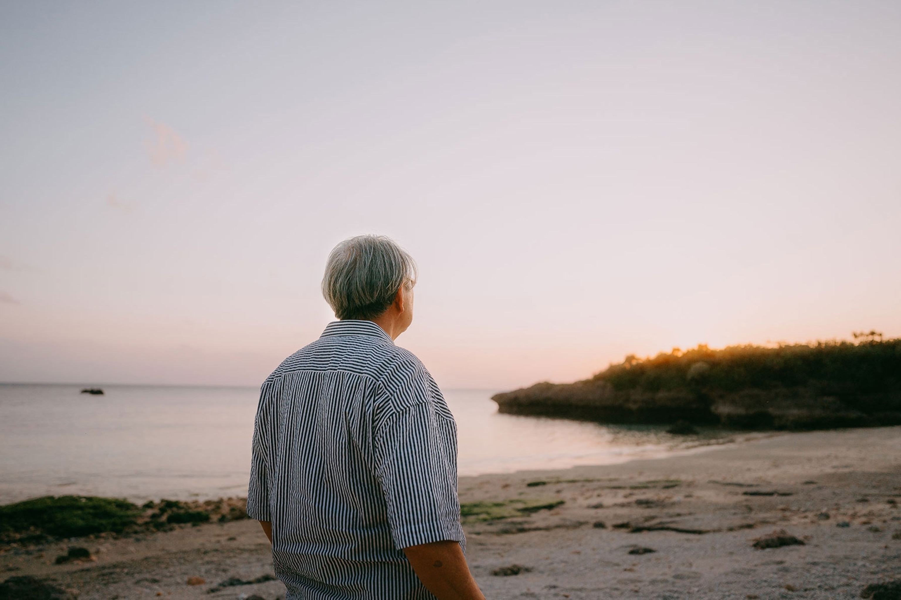 Senior man looking at sunset on beach
