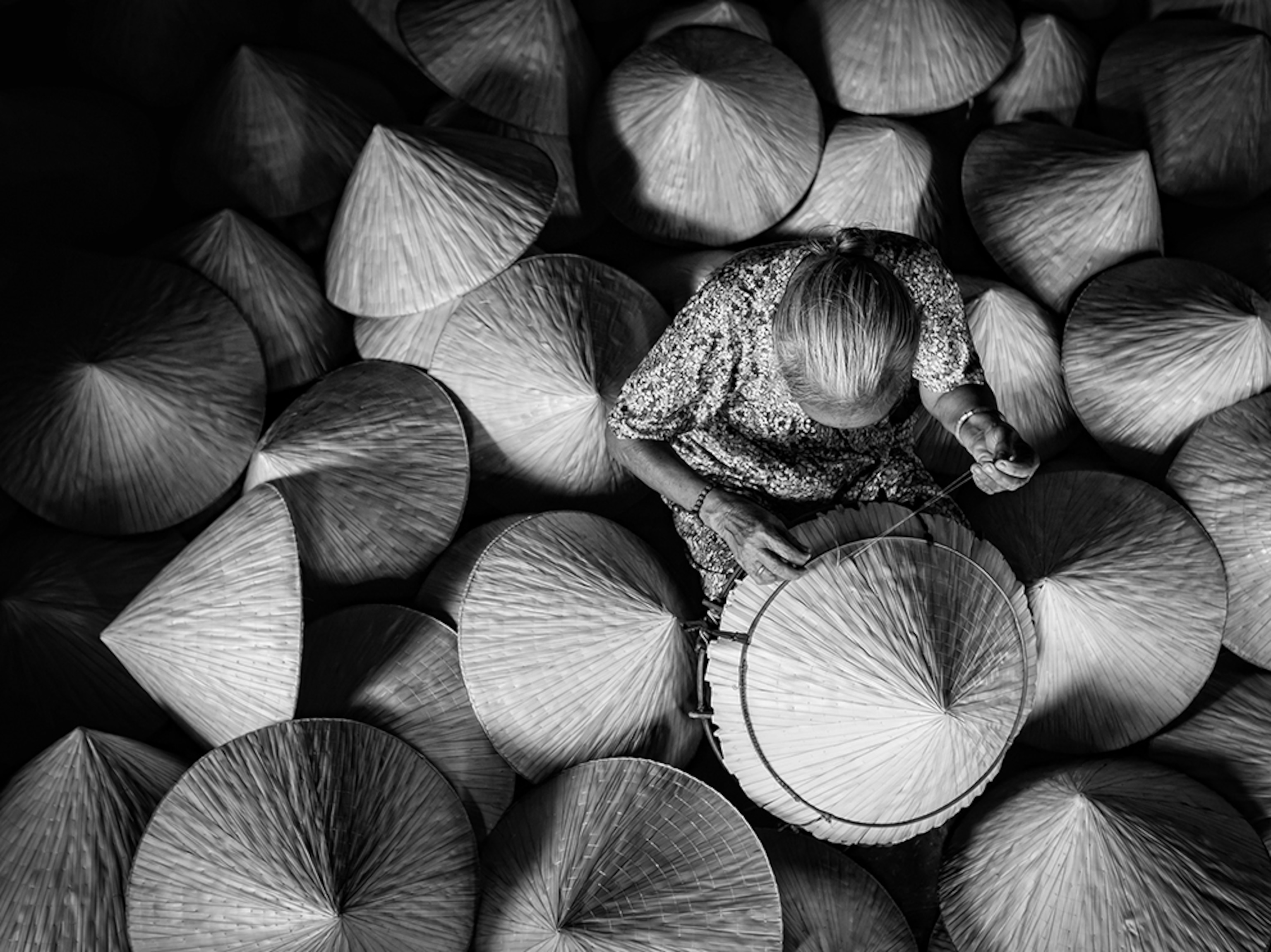 a woman making conical hats out of palm leaves in Duc Hoa, Vietnam