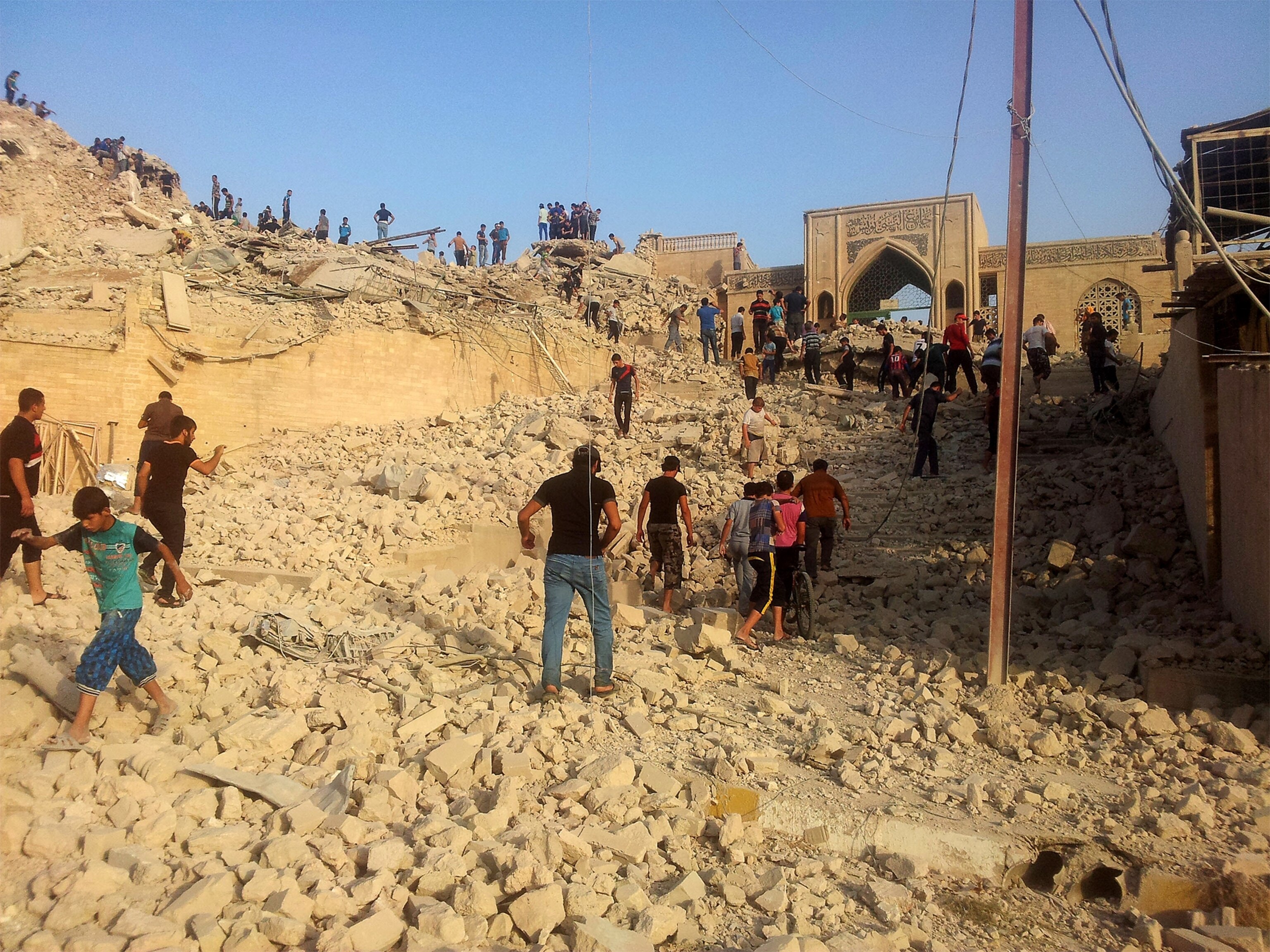 a person riding a bicycle in front of the destroyed Prophet Jirjis mosque in central Mosul.