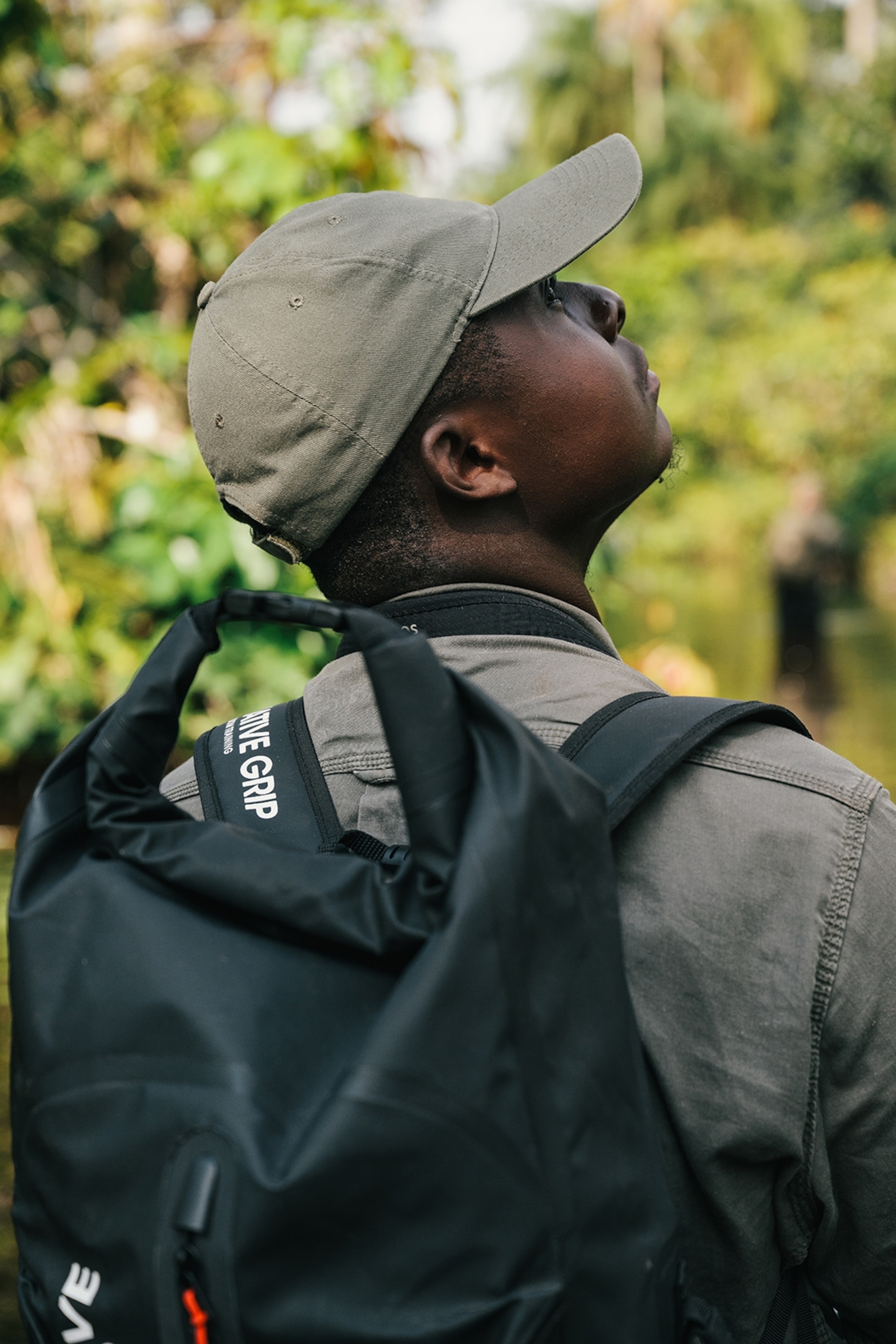 A local guide looking up at a rainforest, photographed from behind.