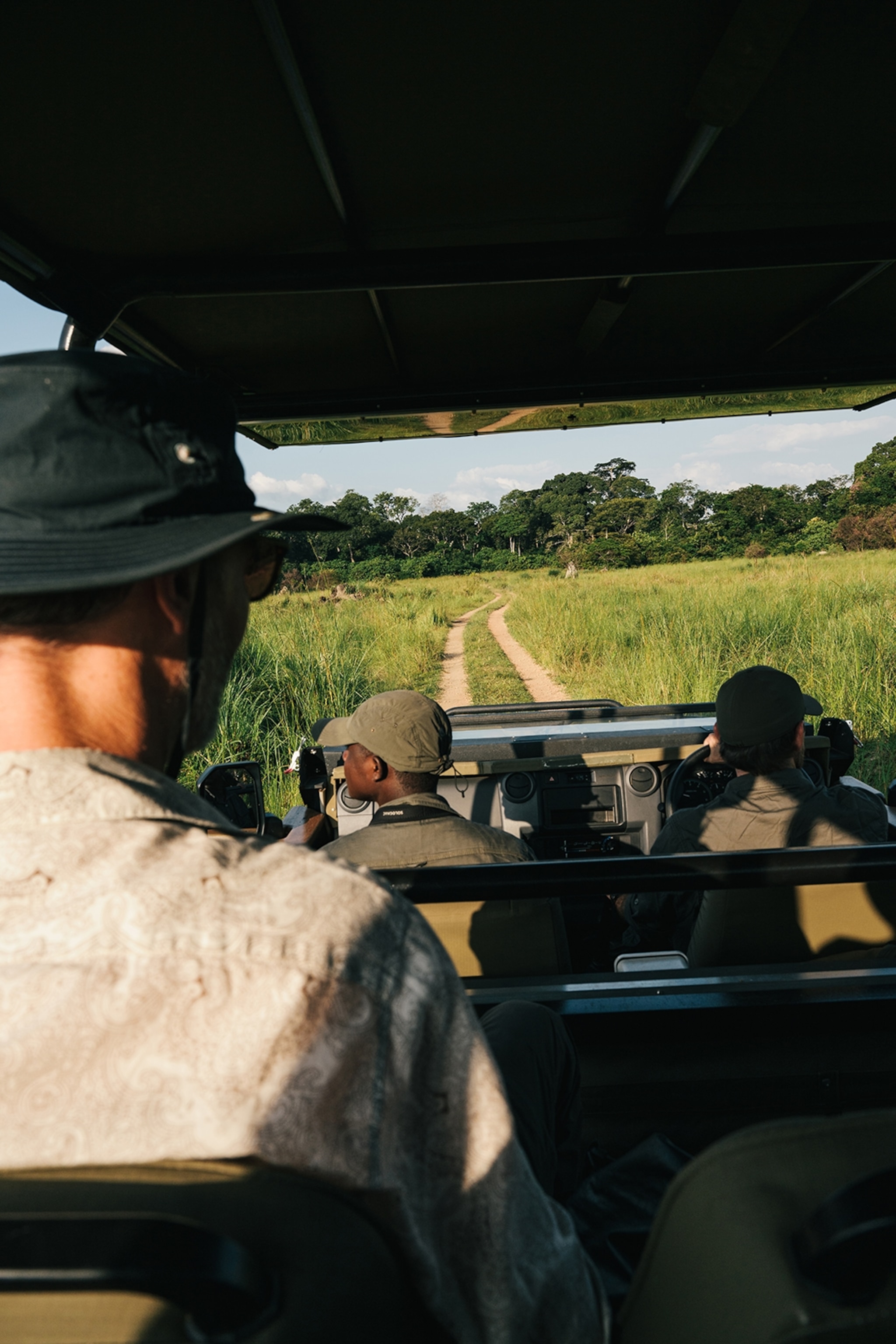 A POV perspective from the back row of a safari car, looking out on the road ahead.