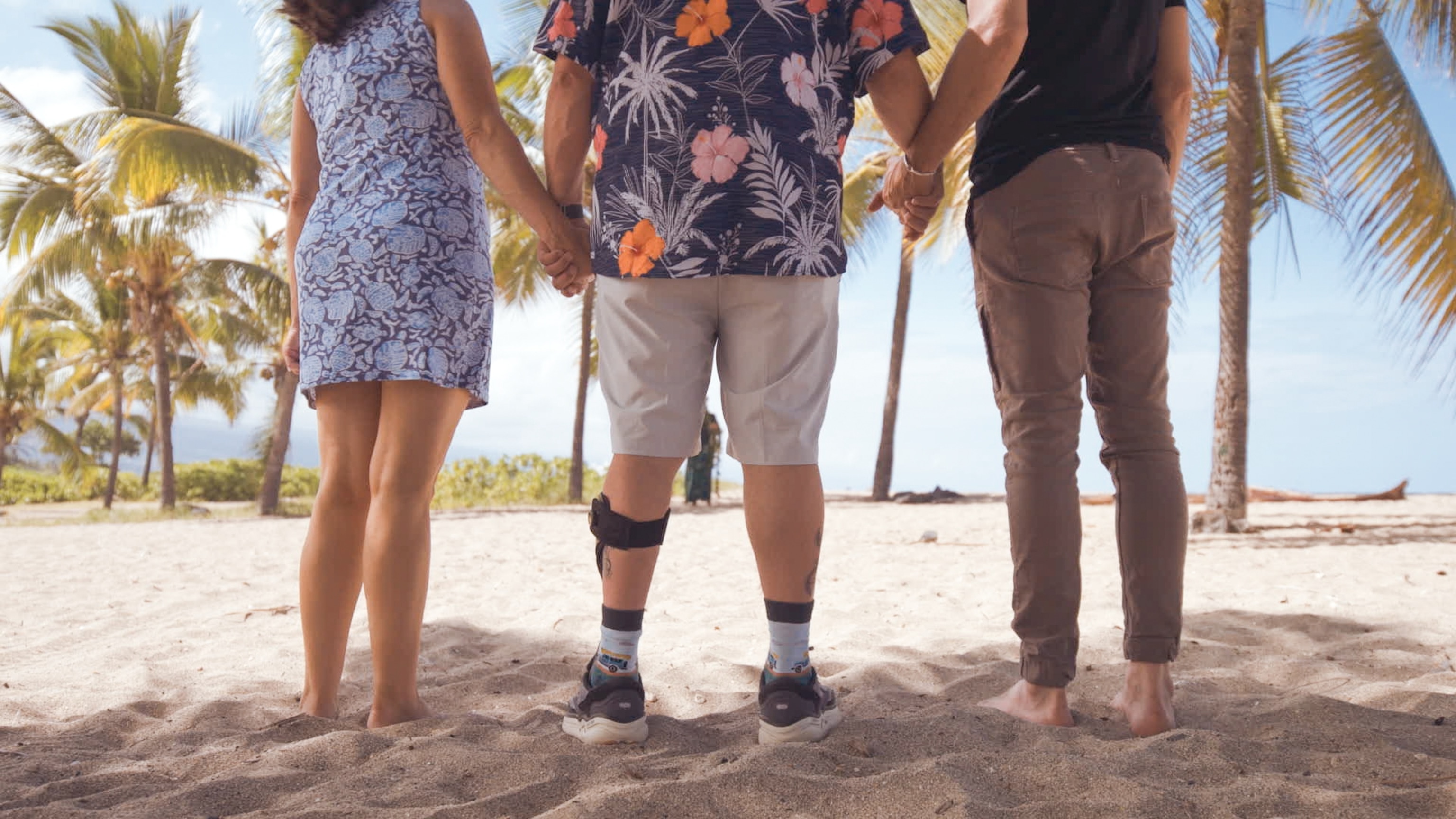 Three people stand on beach in Hawaii