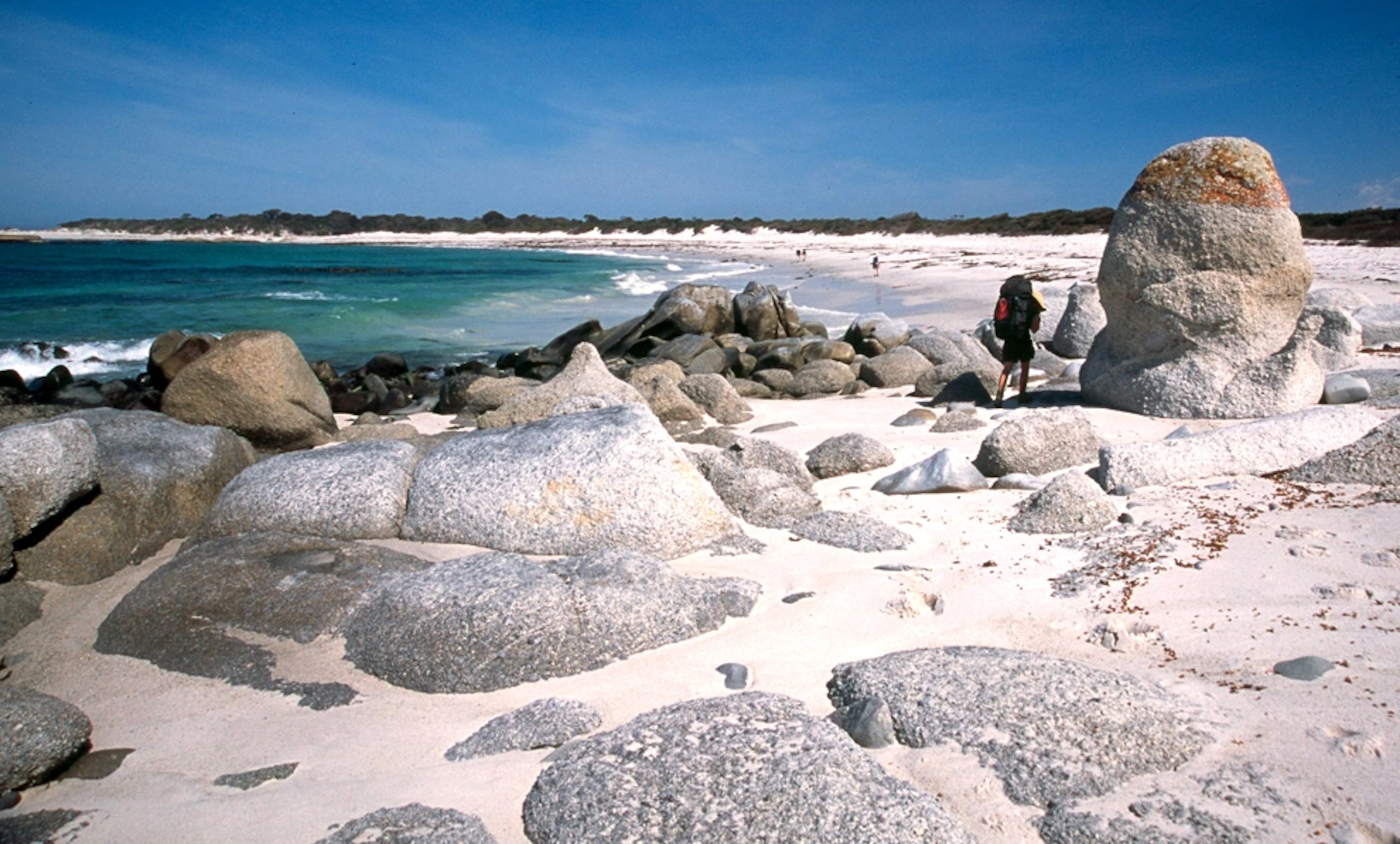 Hiker on the beach along the Bay of Fires trail in Tasmania