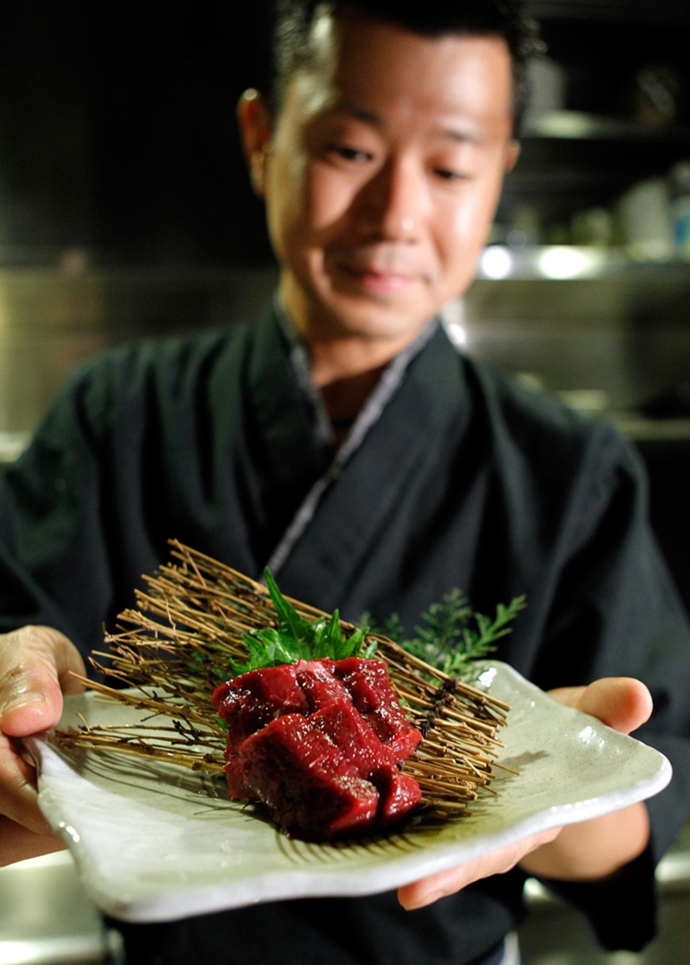 Whale sushi held by a chef.