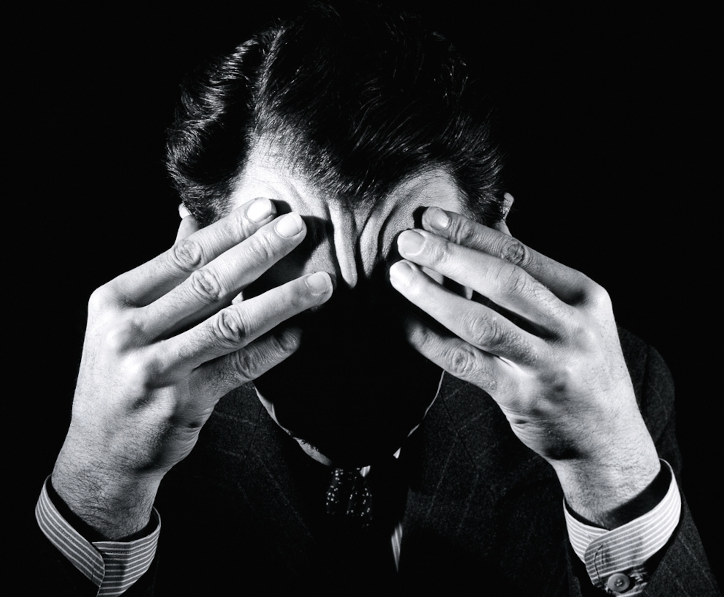 A man with a headache holds his head.