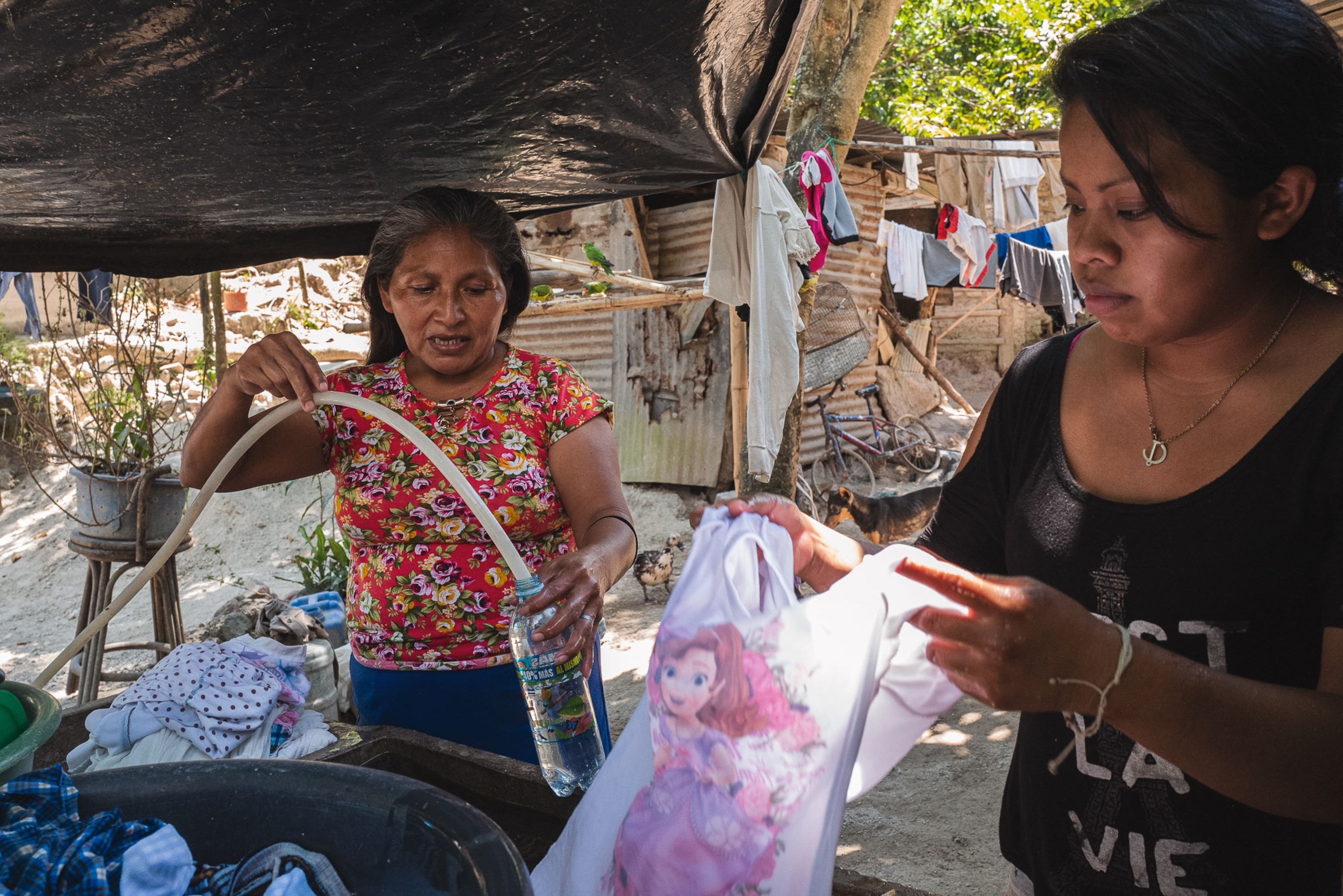 a woman fills a water bottle with water from a cantarera in El Salvador
