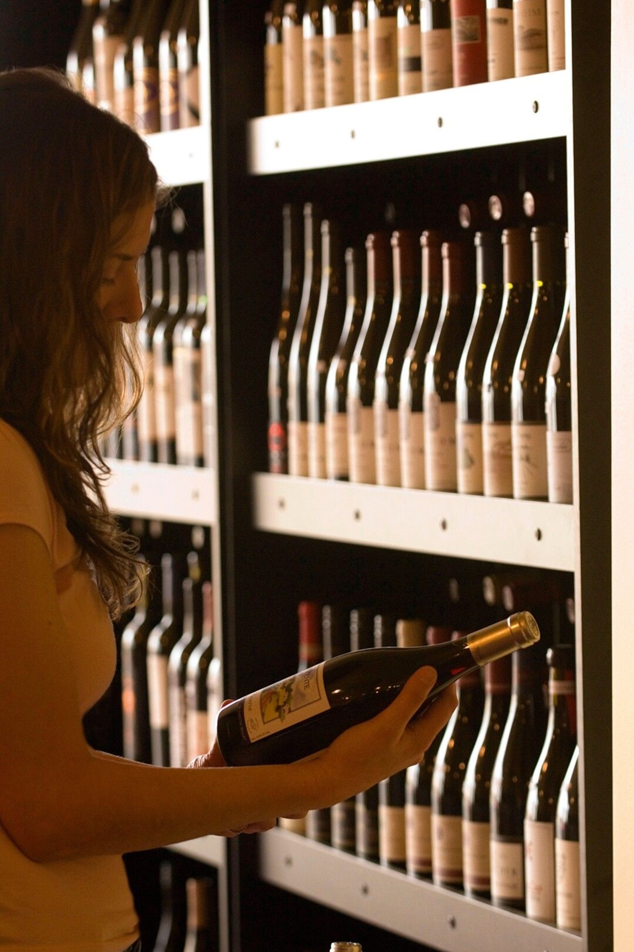 A woman holding a bottle of Pinot Noir at Liner & Elsen wine merchants.
