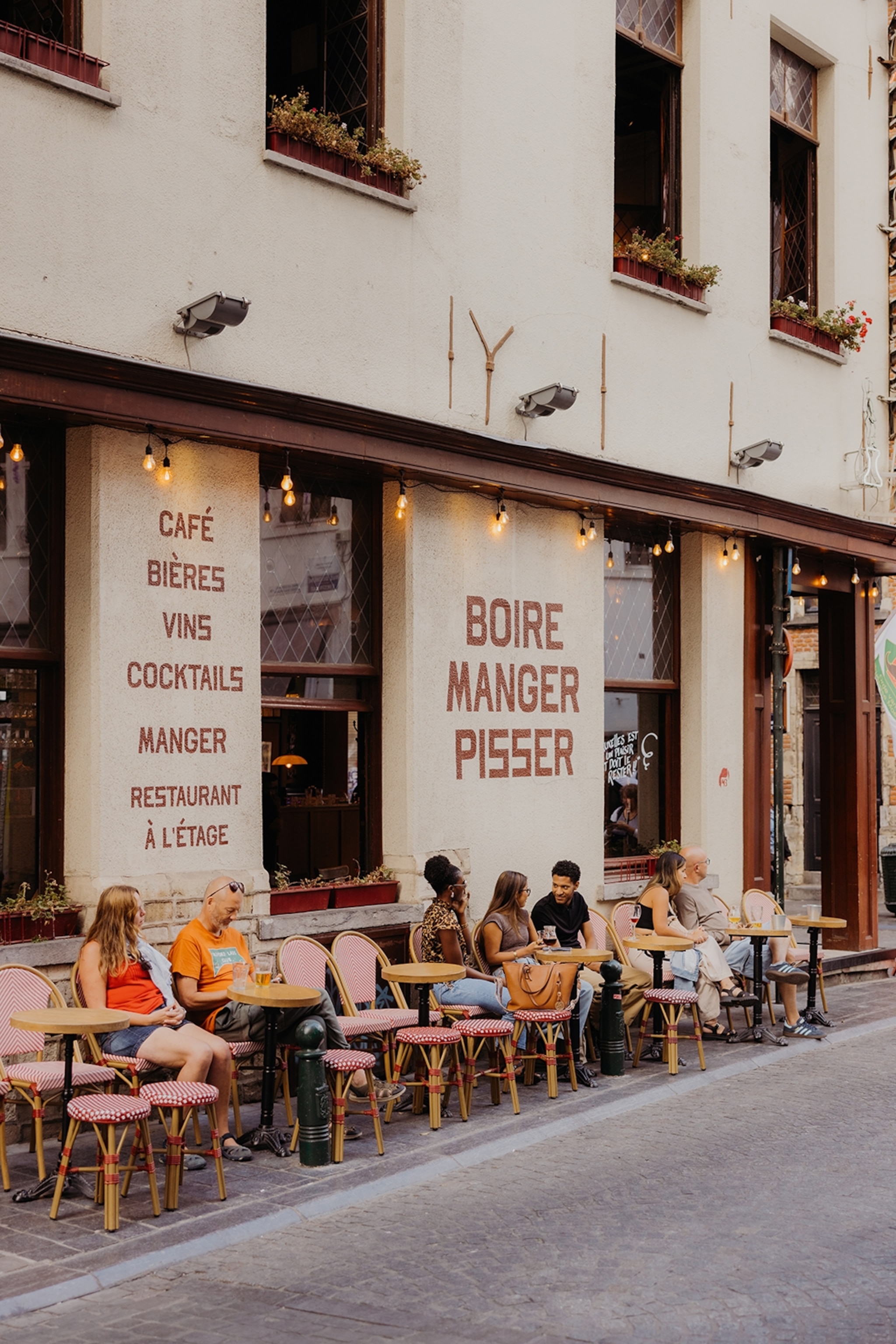 The exteriors of a cafe also serving beer and wine with street-side, bistro-style seating.