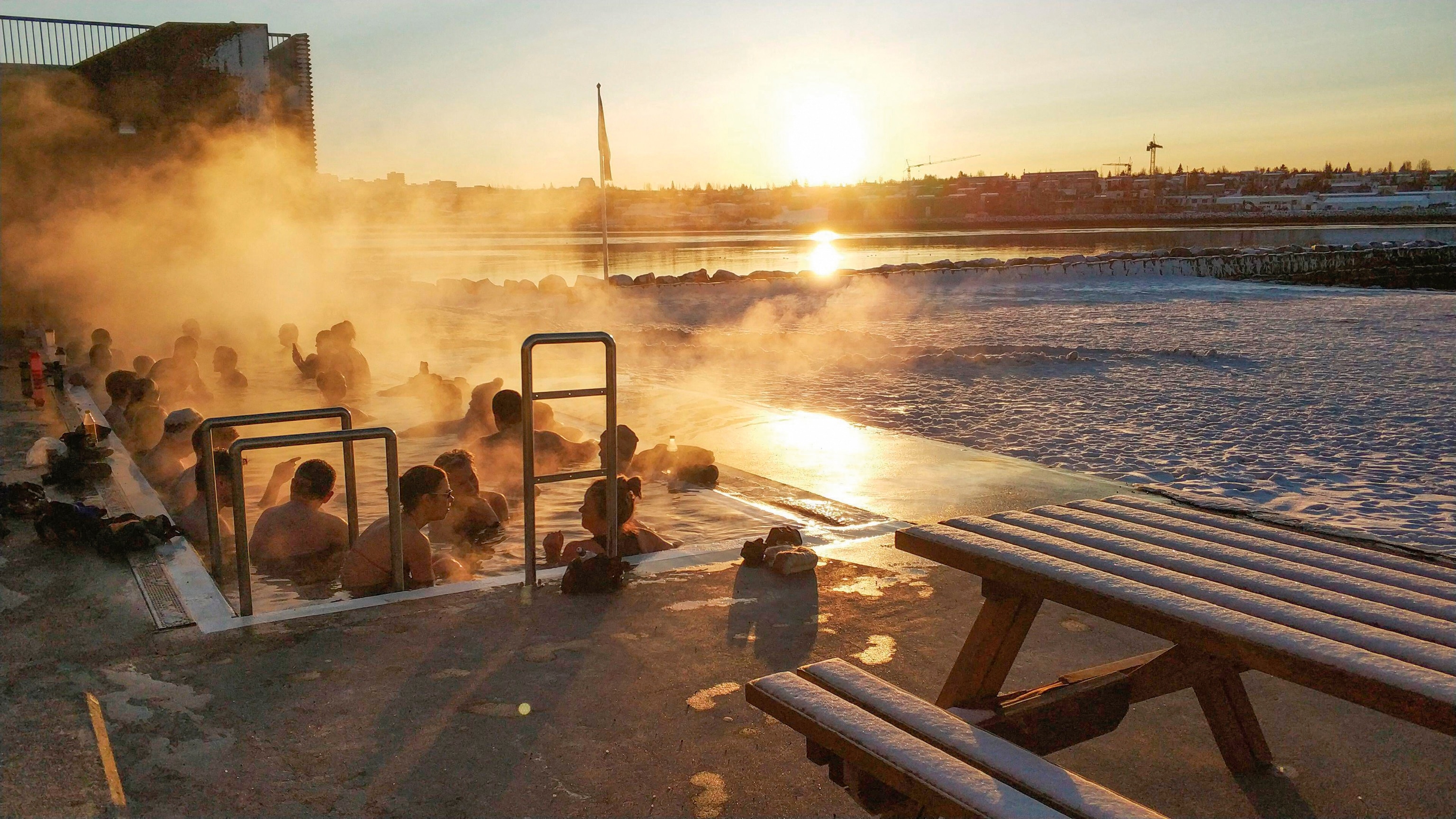 A group of people bathing in the Nauthólsvík open-air tubs after an icy dip in the sea.