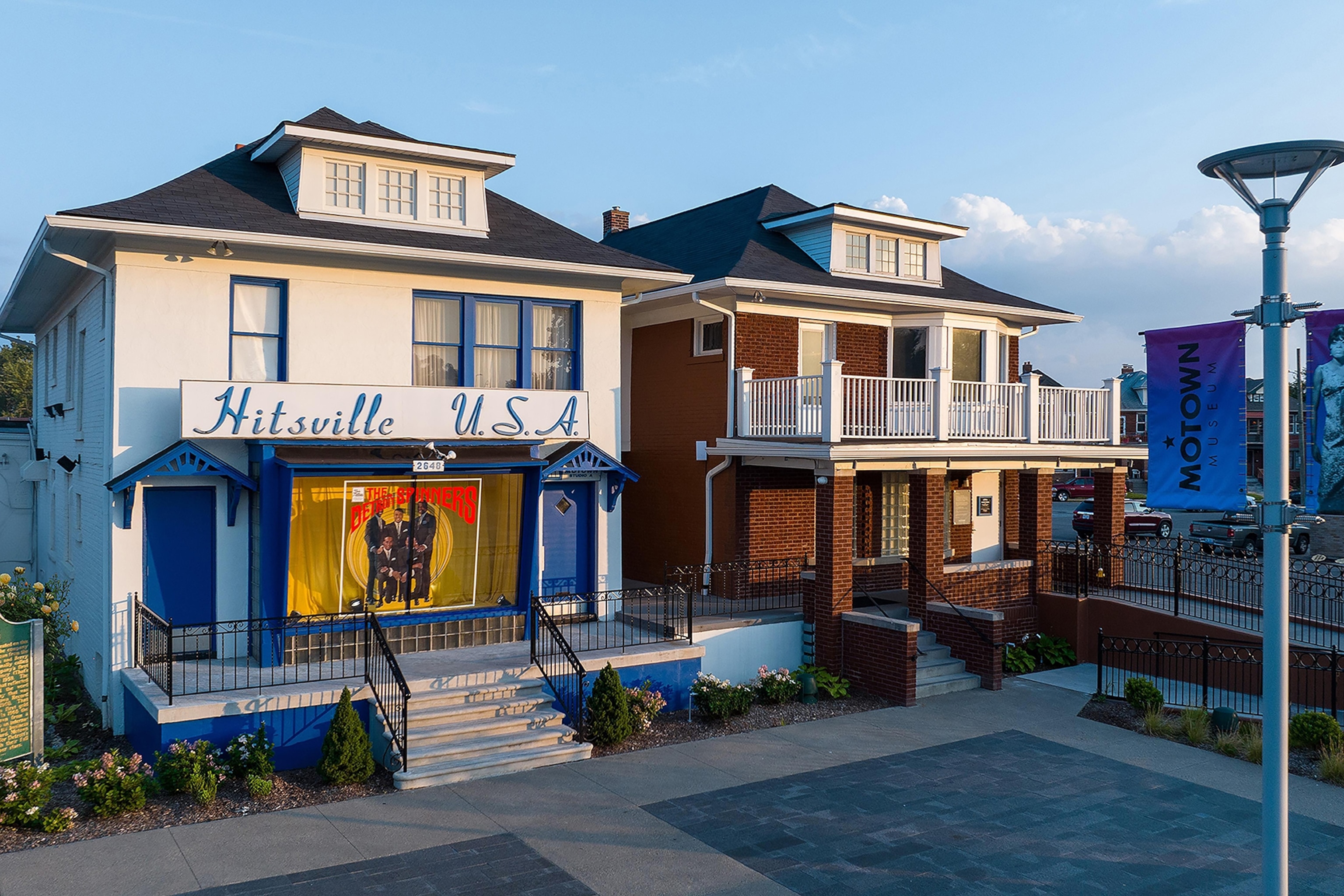 Exterior of two houses, one which is painted in blue and white and has a large overhead sign reading 'Hitsville U.S.A'