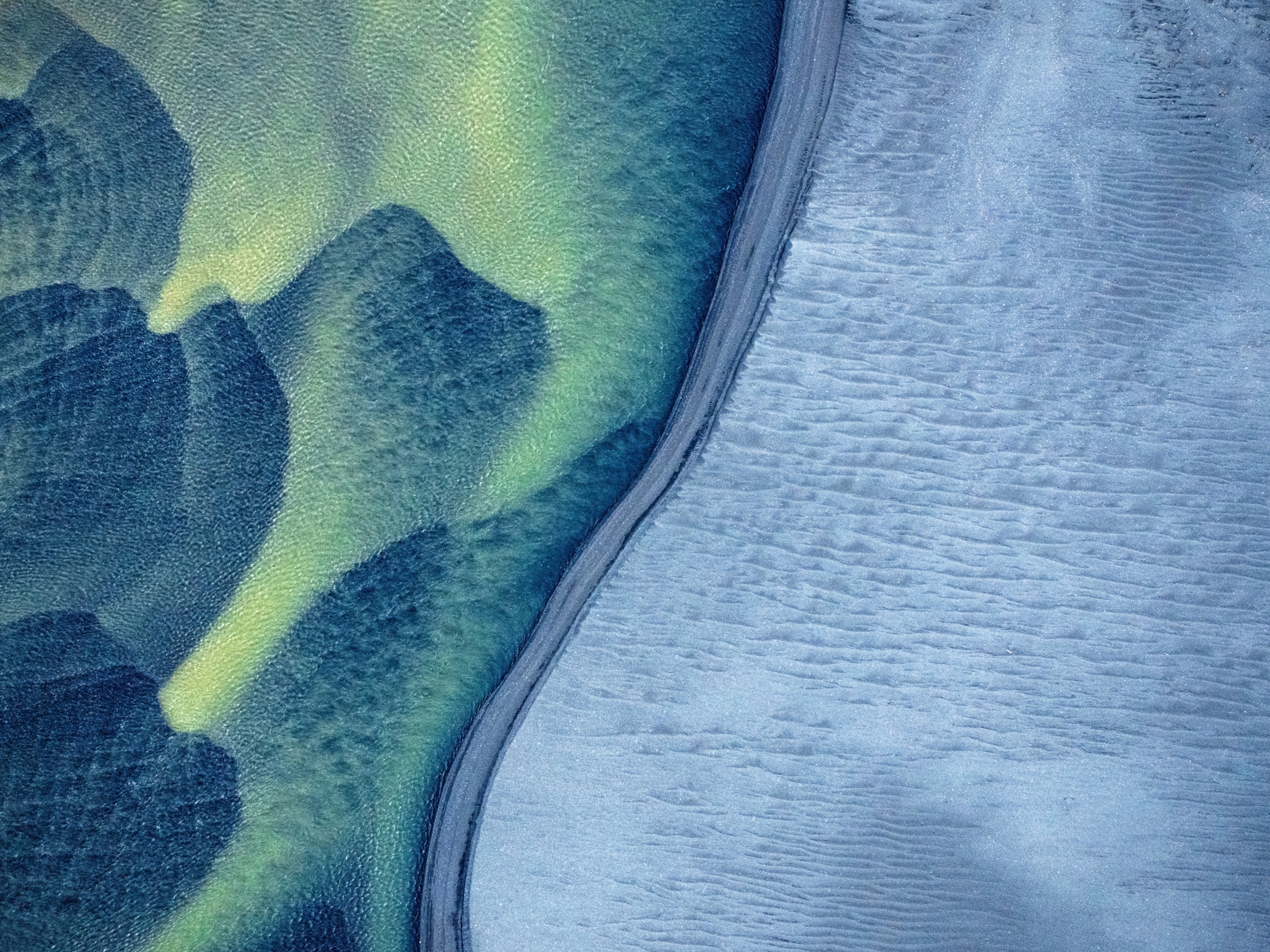 Aerial view of a winding river dividing two landscapes: textured, wavy sand dunes on the left in green and smooth, icy terrain on the right in blue.