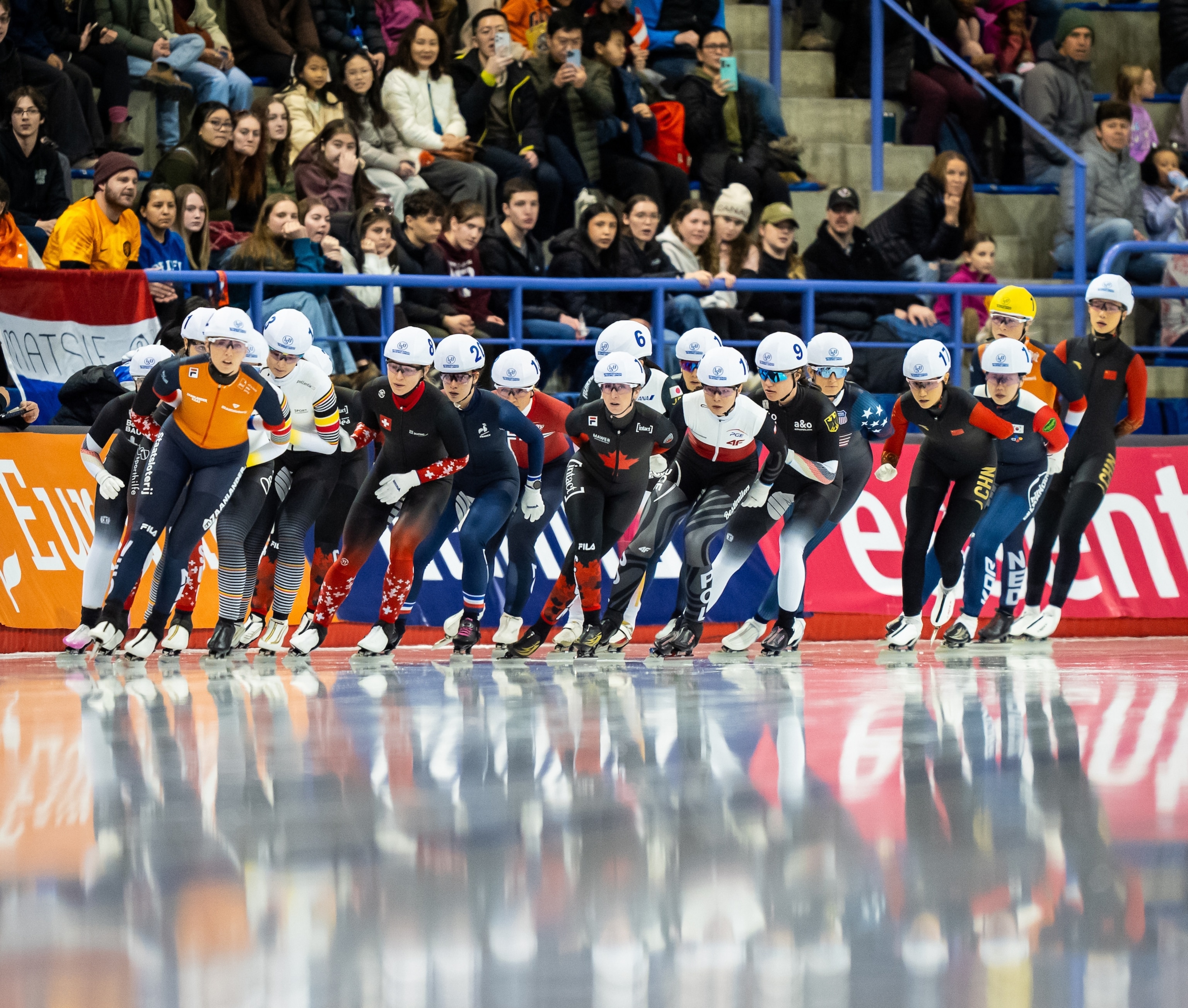 A group of people ice skate on a rink