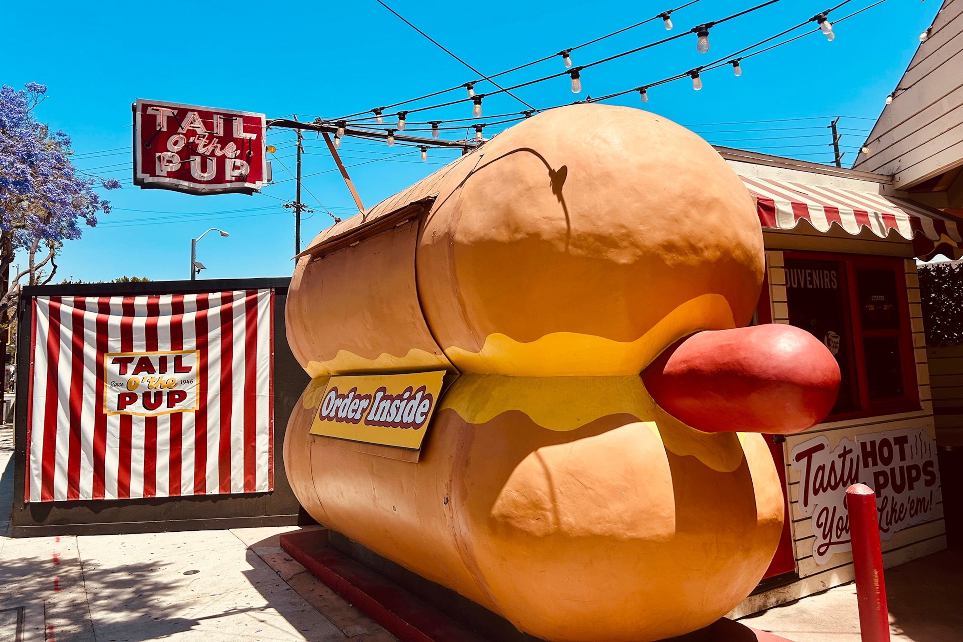 A hot-dog-shaped roadside stand with a hatched that opens and hot dogs are sold out of.