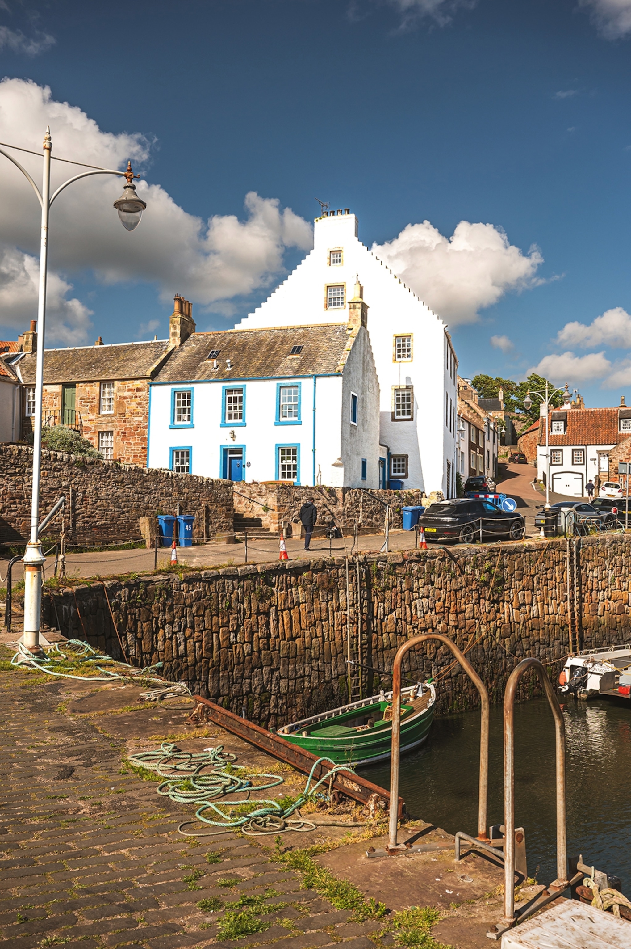 A calm harbour scene with a focus on the stone walls and pyramidical houses of the picturesque village.