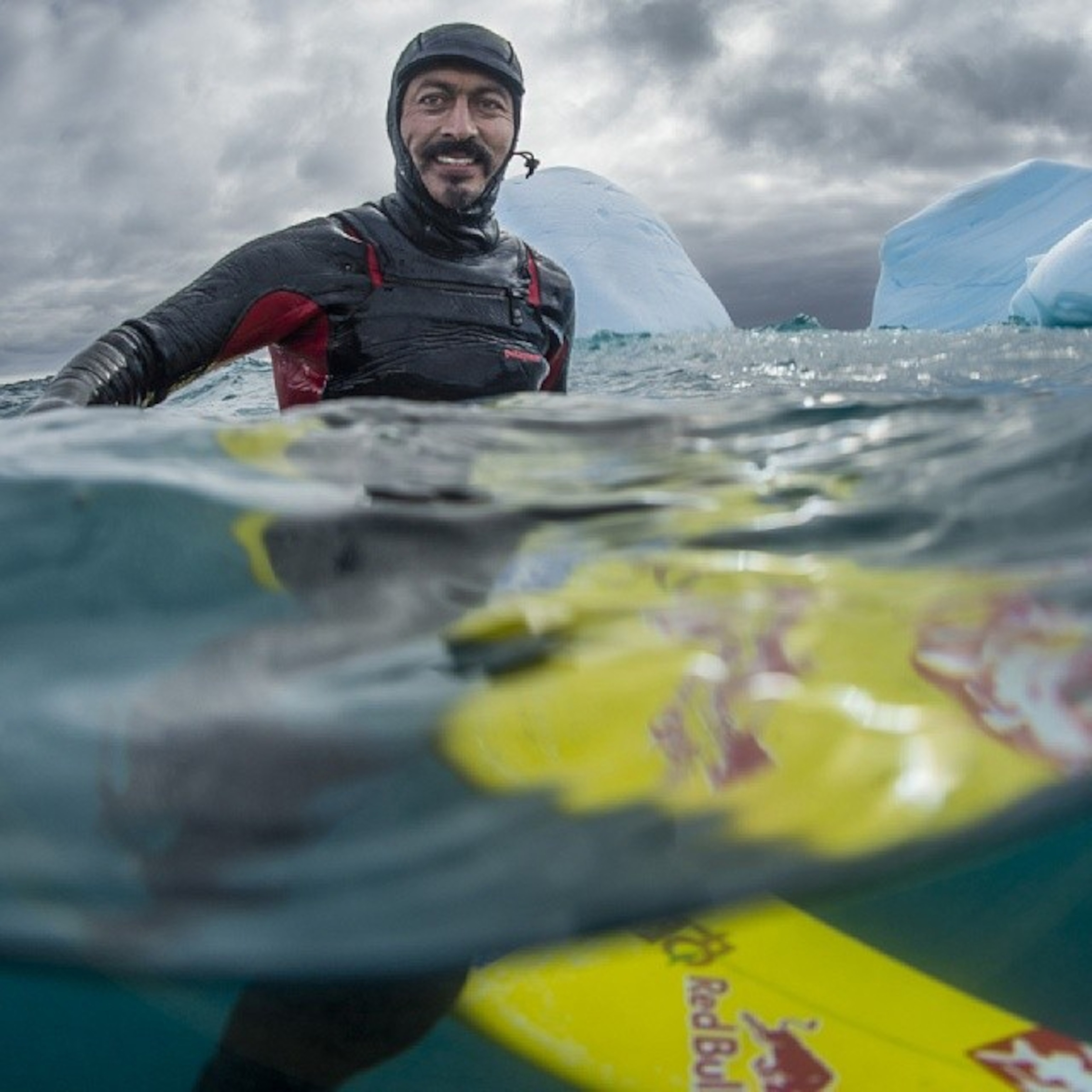 Ramon Navarro sitting on a surfboard in Antarctica