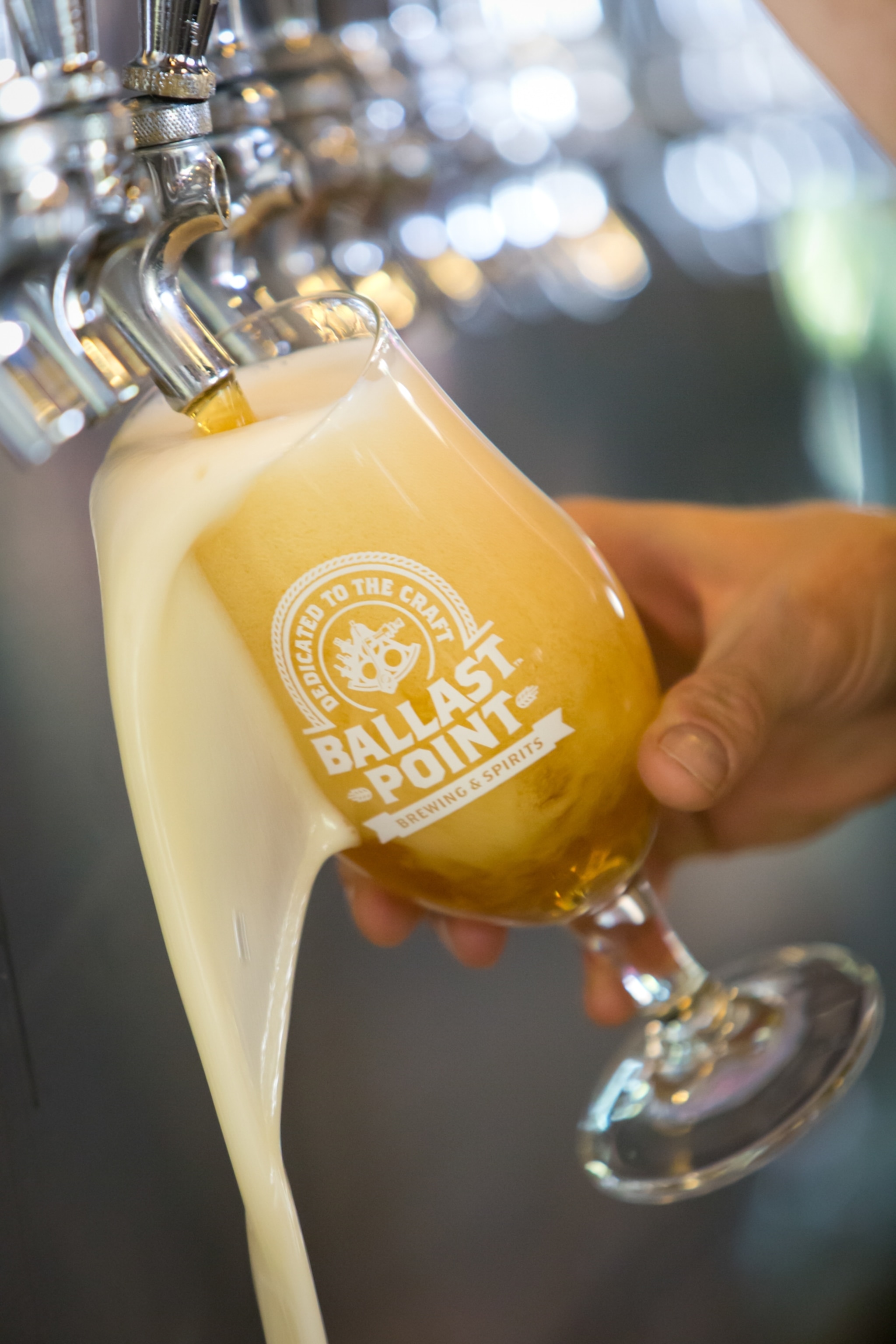 A close-up view of beer being poured into a glass displaying the Ballast Point name and logo