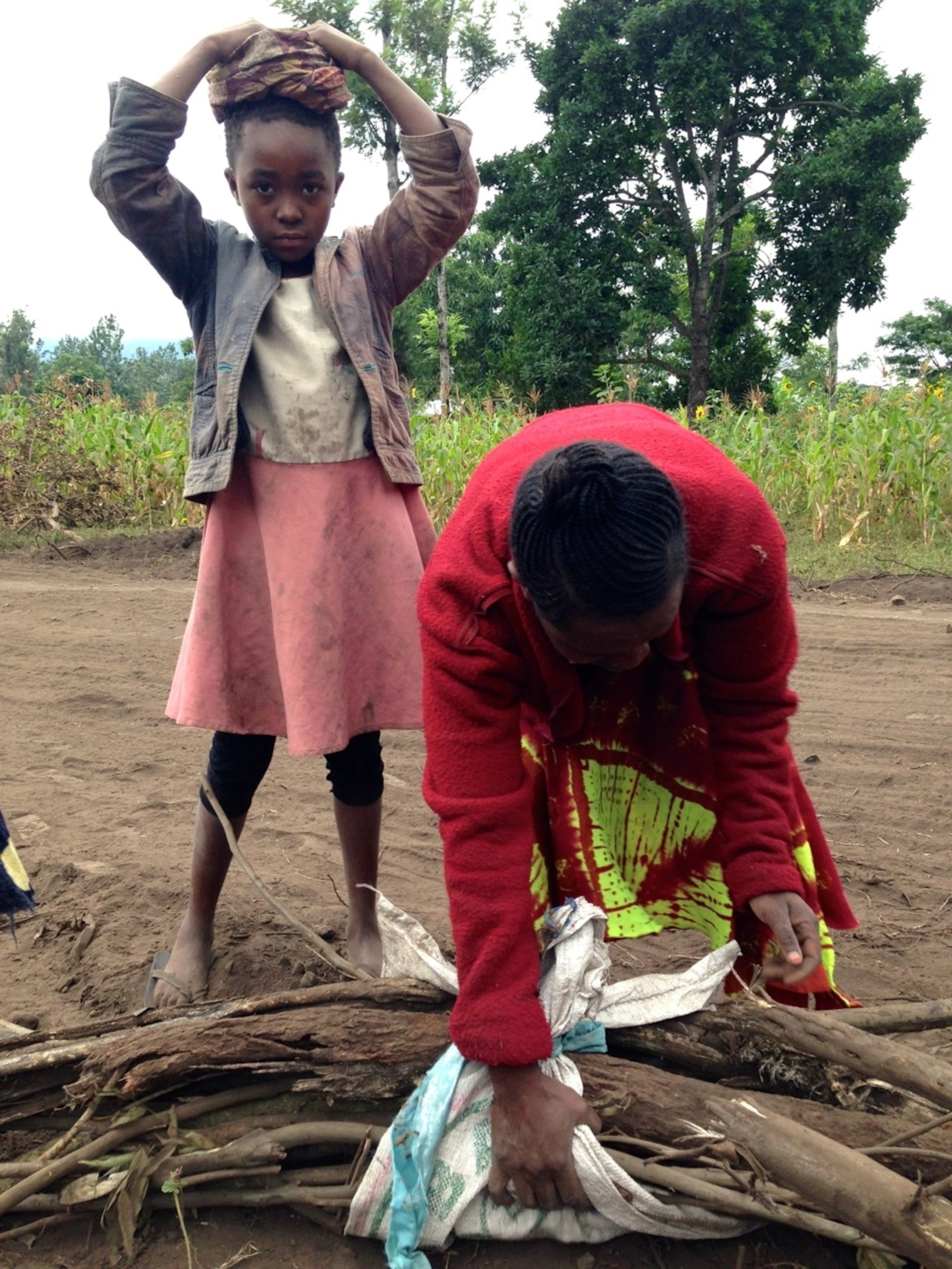 Deborah (background) and Josephine (foreground) prepare to carry large bundles of firewood on their heads. (Photo by Andrew Evans, National Geographic Traveler.