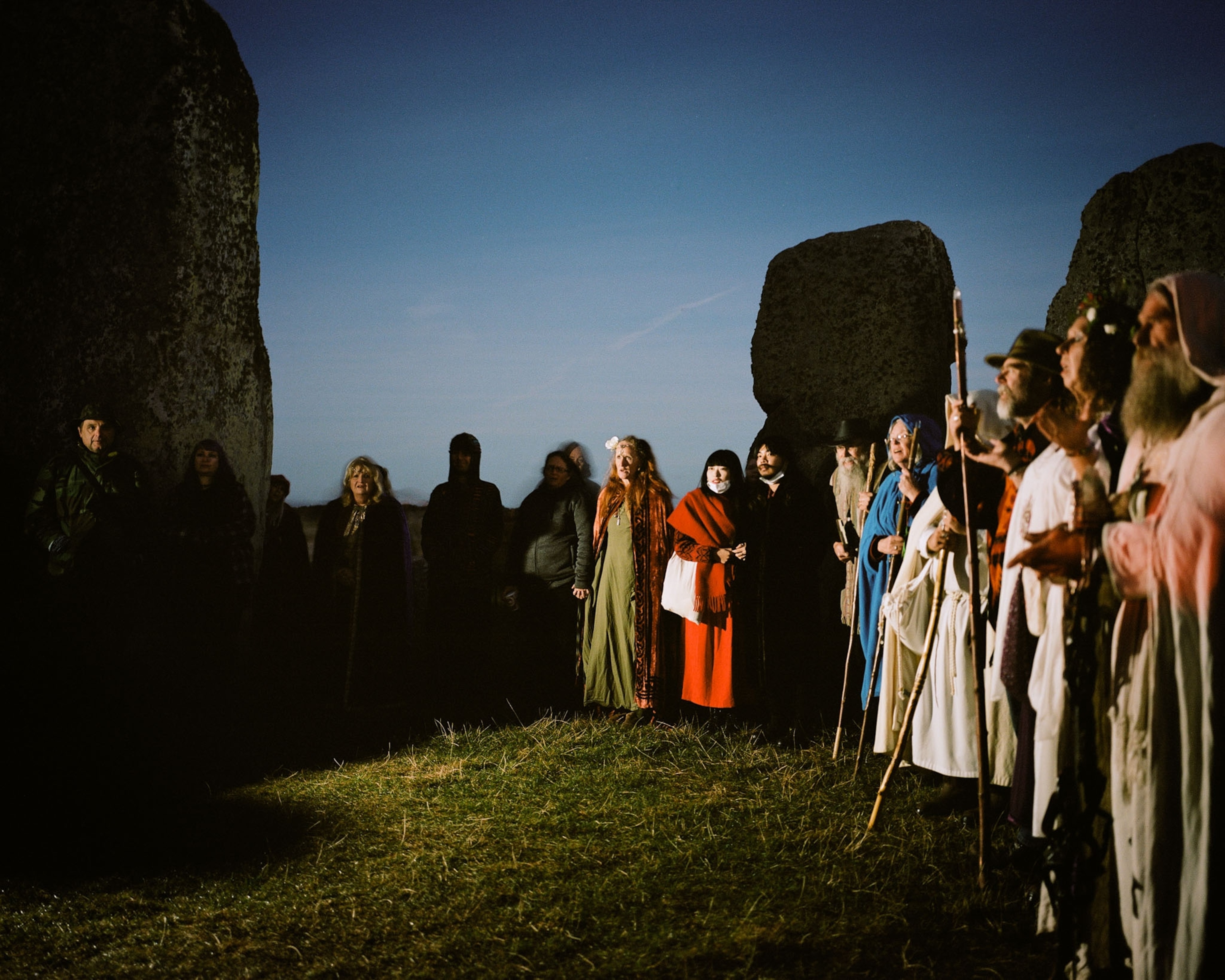 A gathering of people in costume standing within Stonehenge circle.