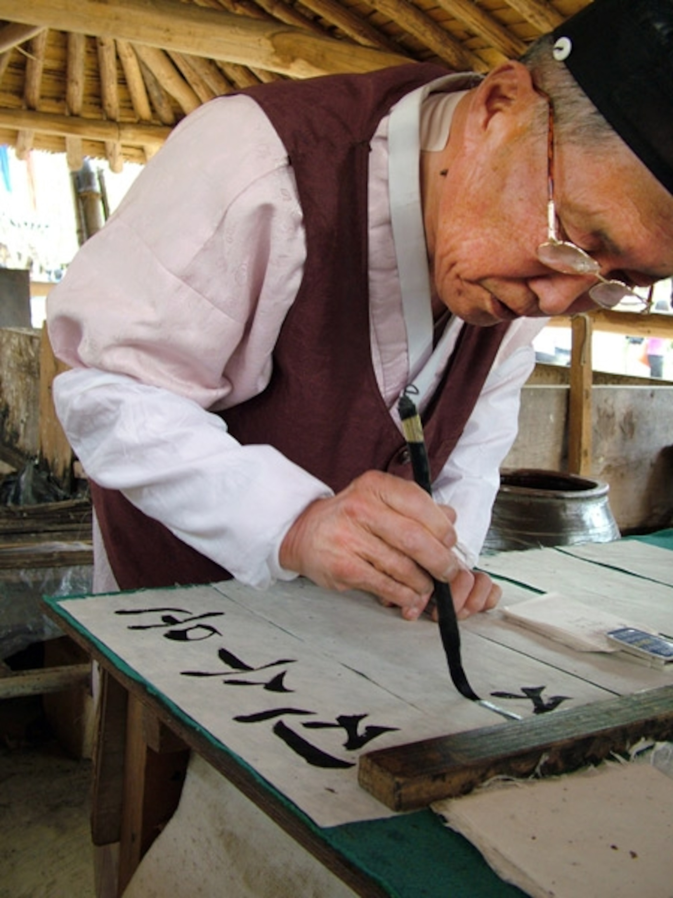An elderly man painting Korean symbols