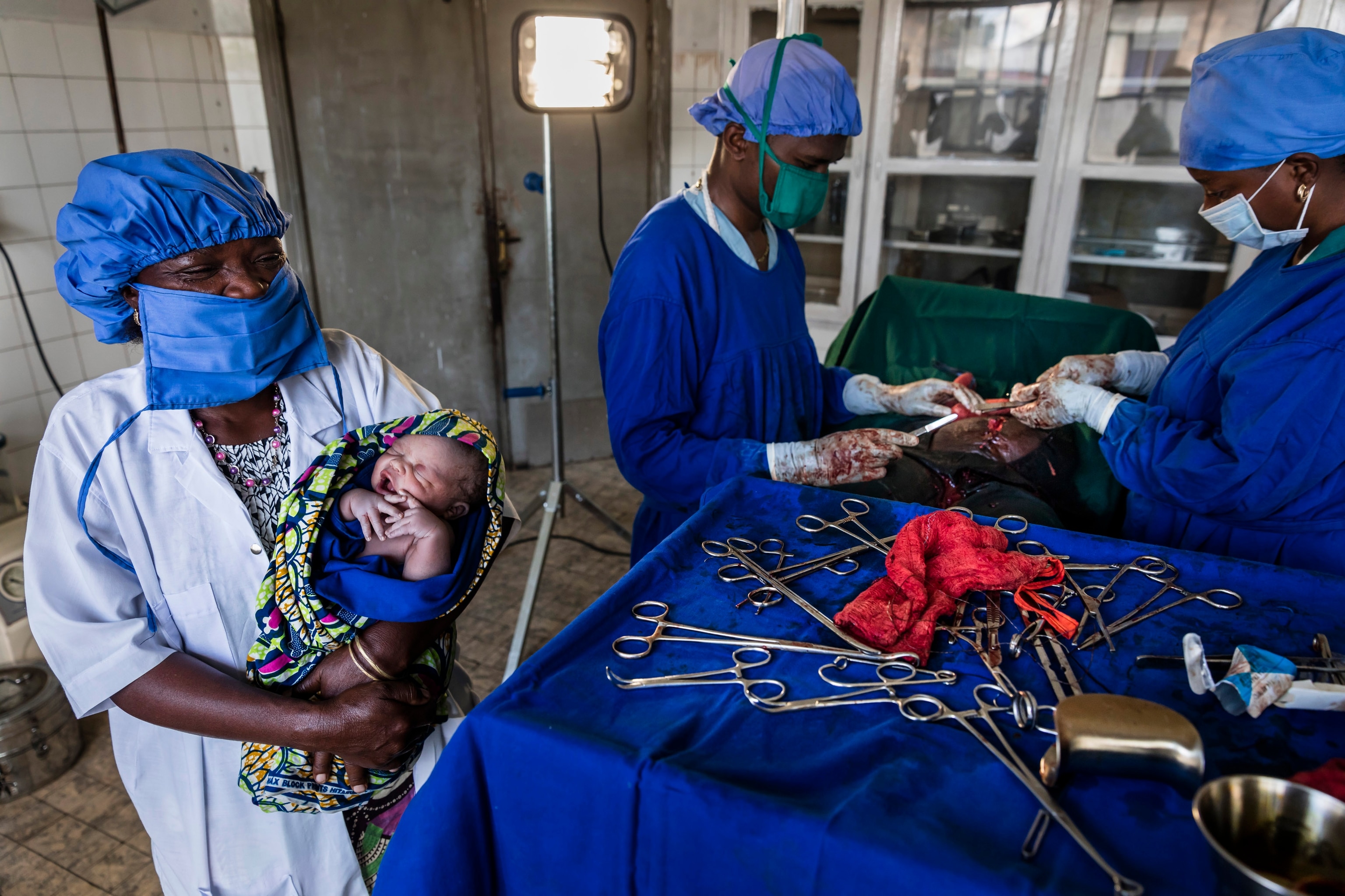 A nurse holding a new baby in a hospital with a light in the background