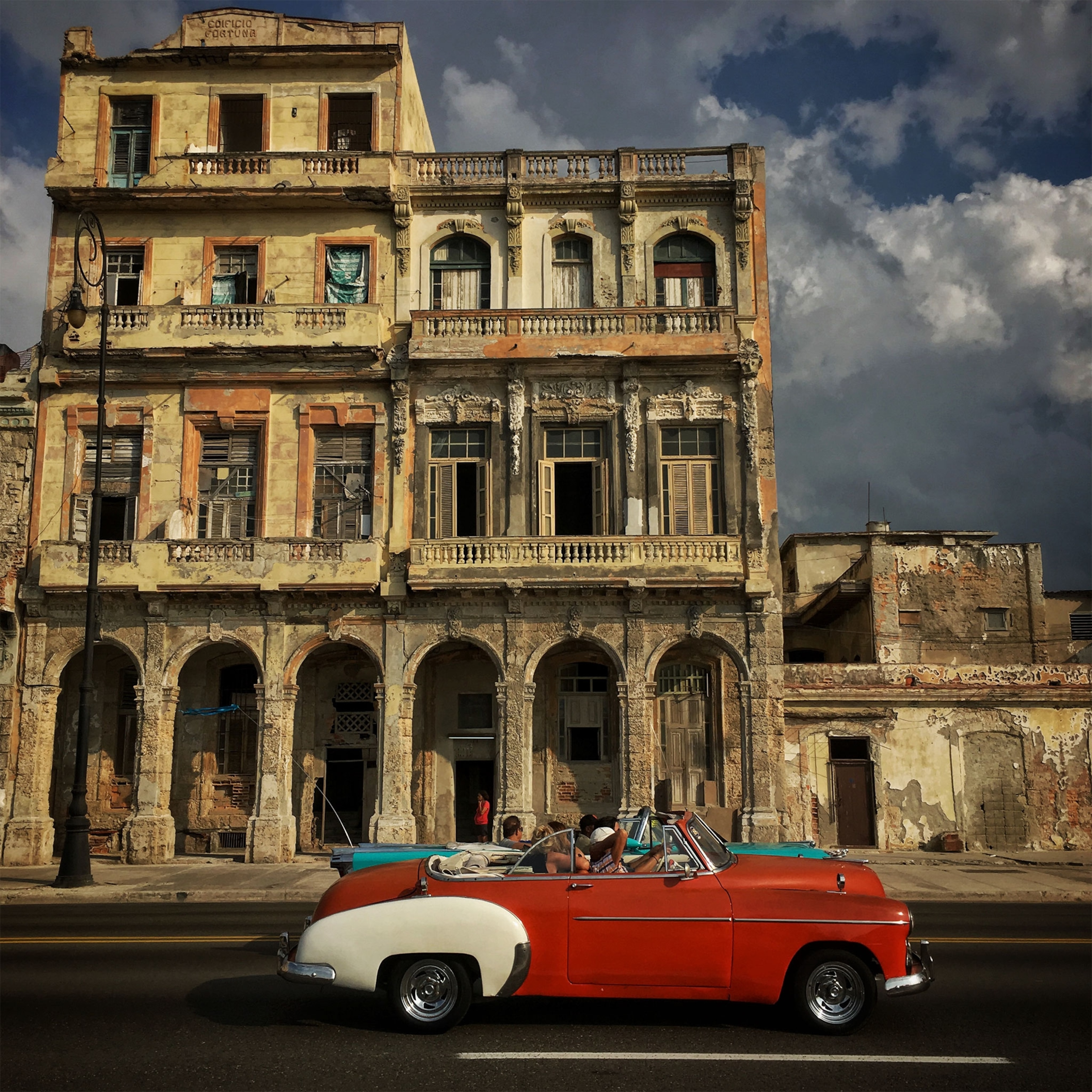 a car driving past old buildings in Havana, Cuba