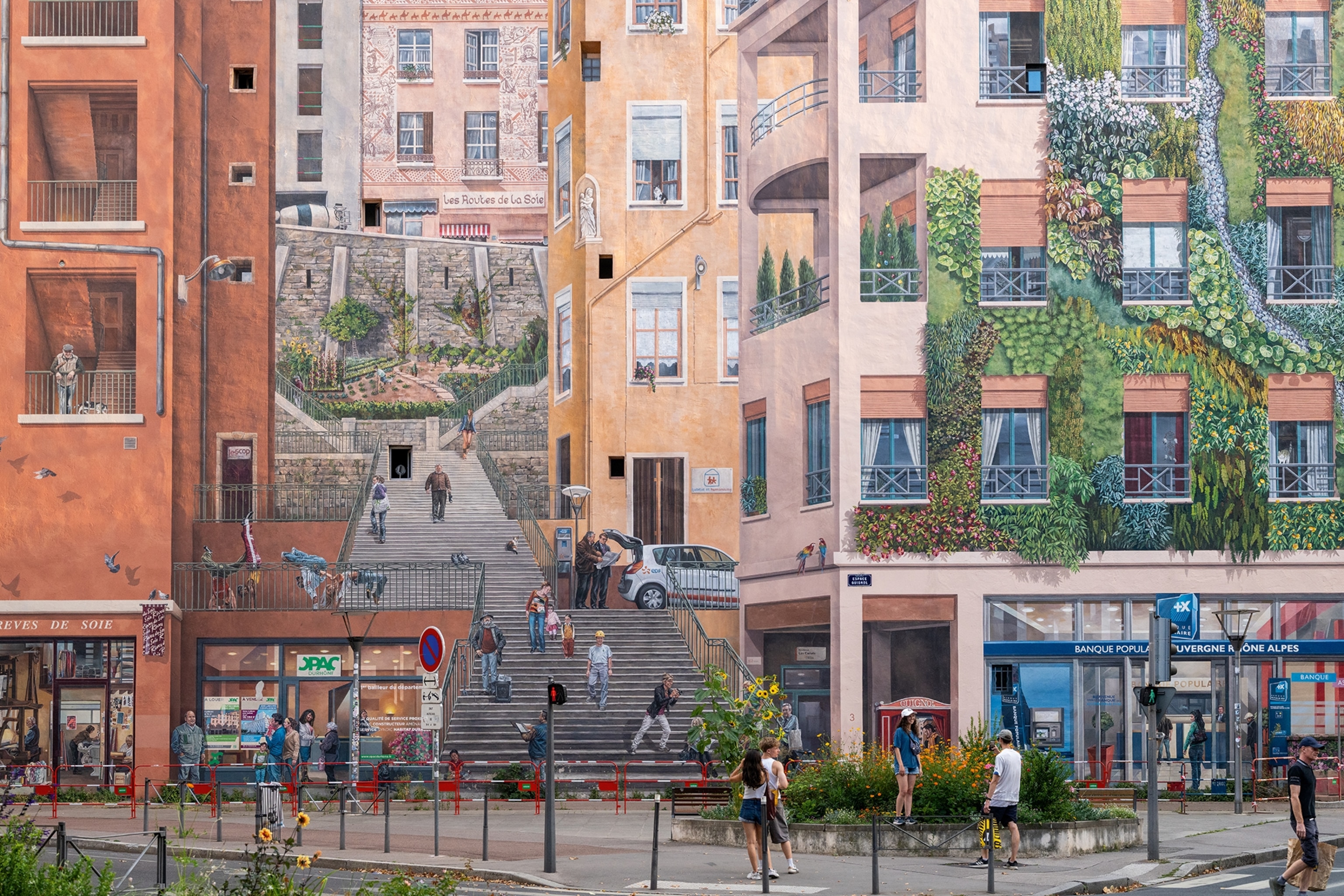 A grand-scale mural on the facade of multiple buildings creating the optical illusion of a staircase winding in between buildings.