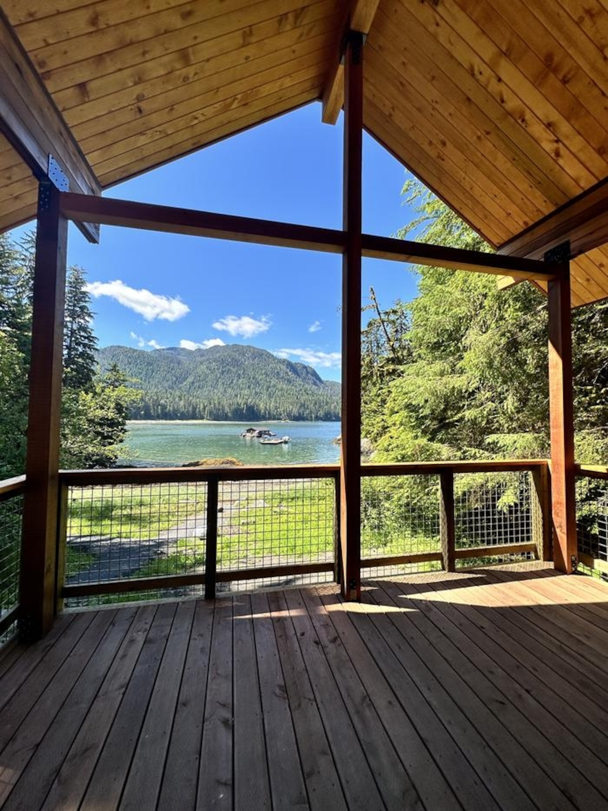 View of a lake and forest from the standing point of a cabin porch.