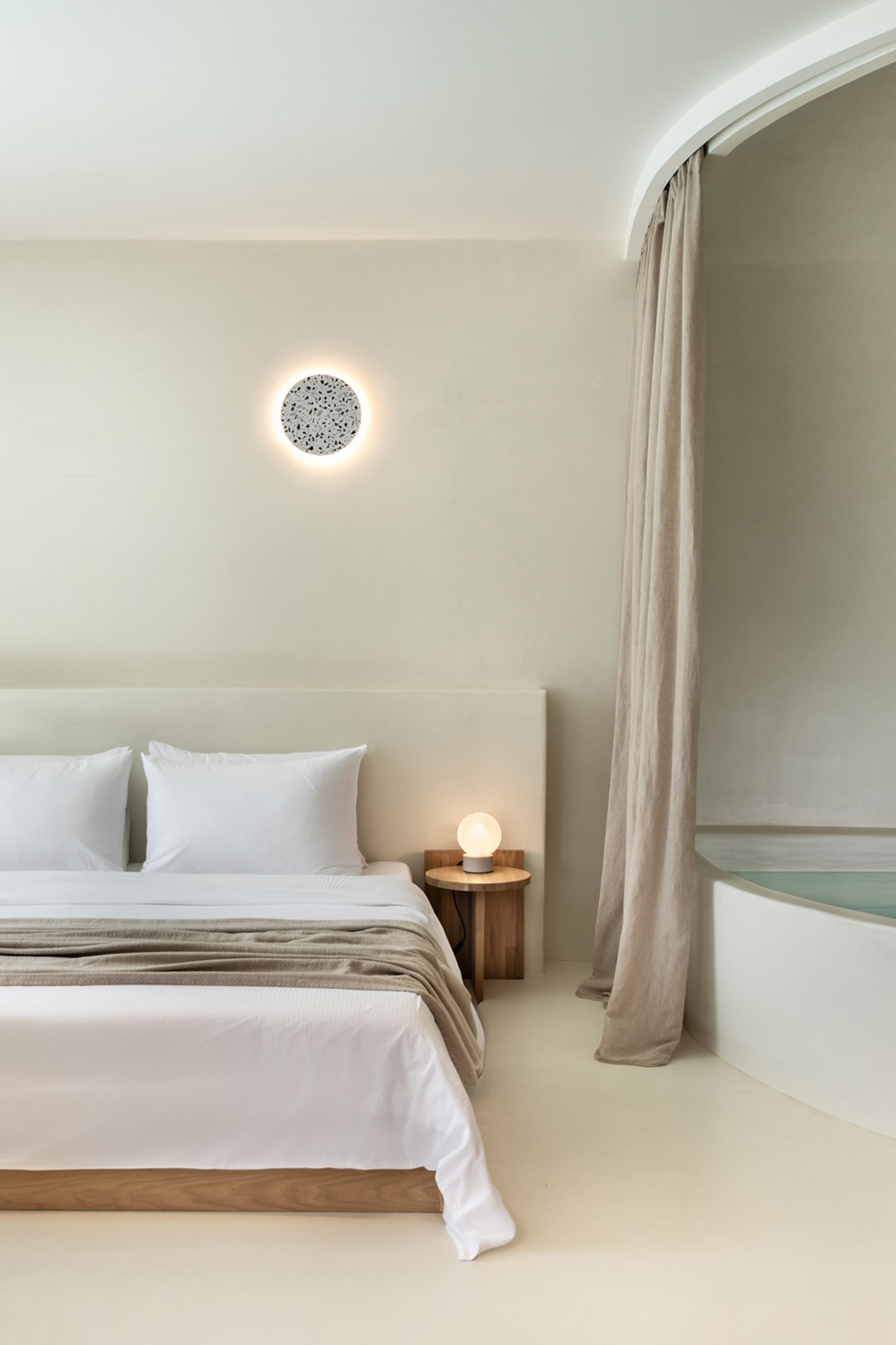 The interior of a sleek and modern hotel room with an infinity pool hidden behind a curtain.