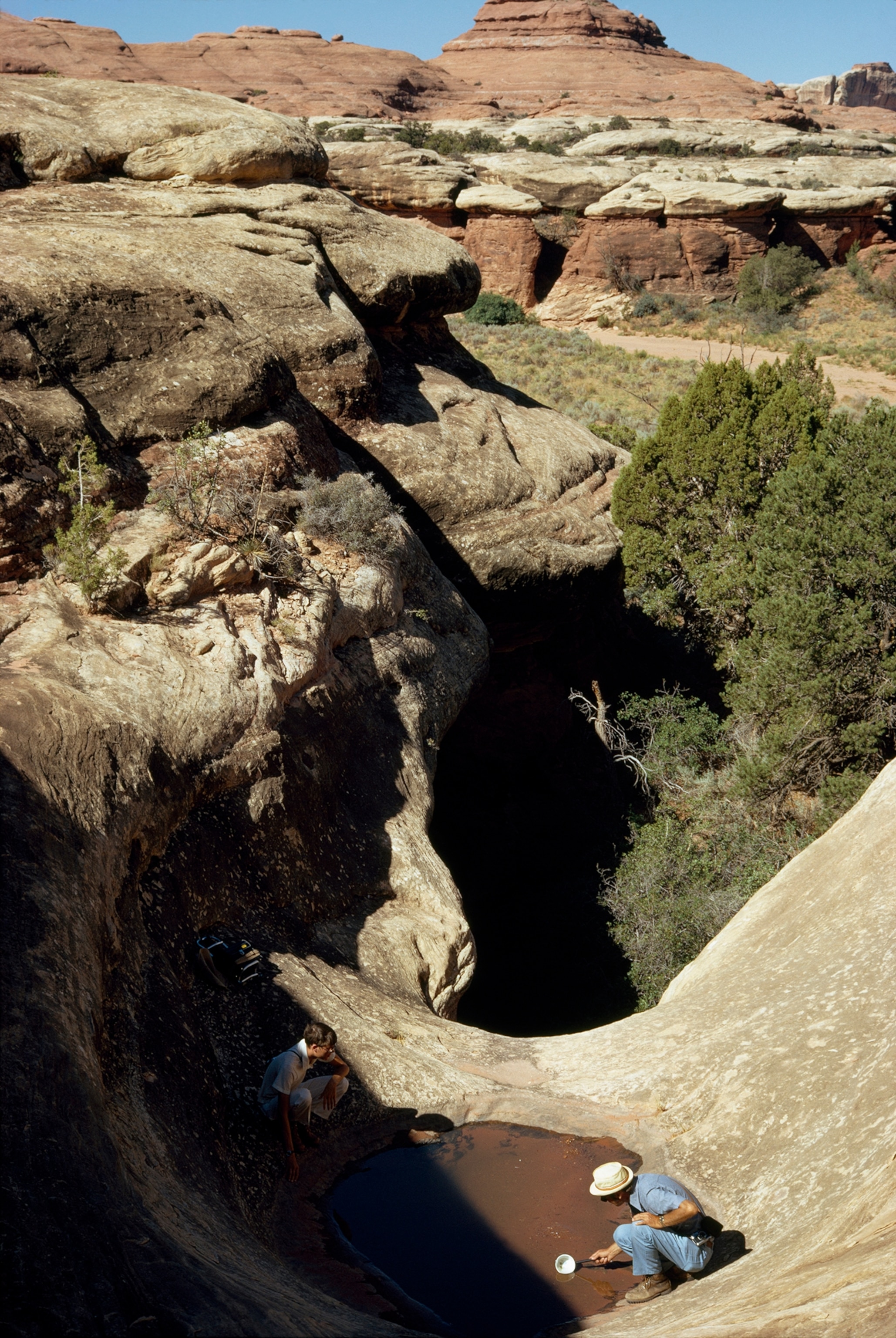 Scientists investigate a desert pothole.