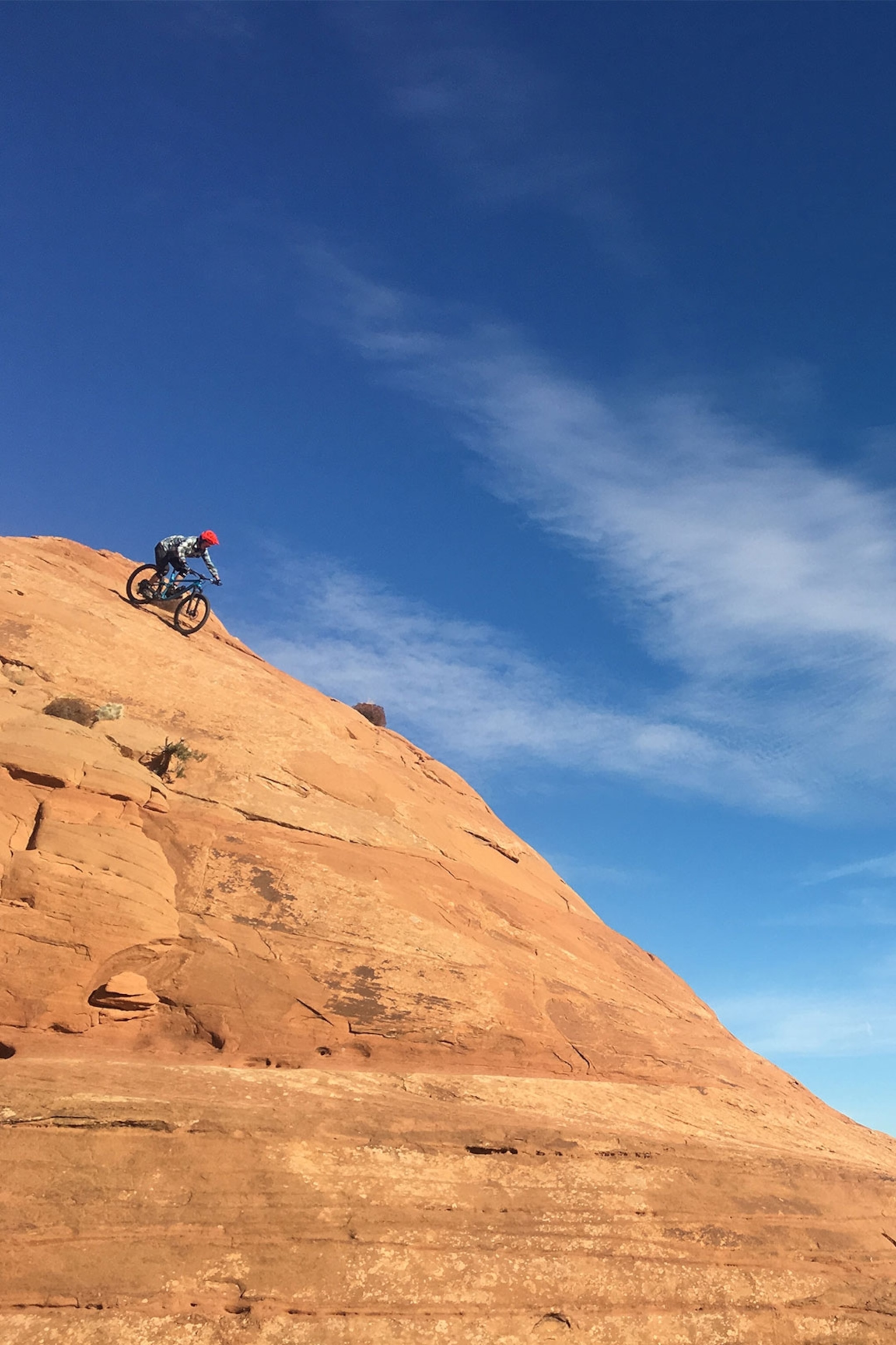 Cyclist descends down steep orange rockface