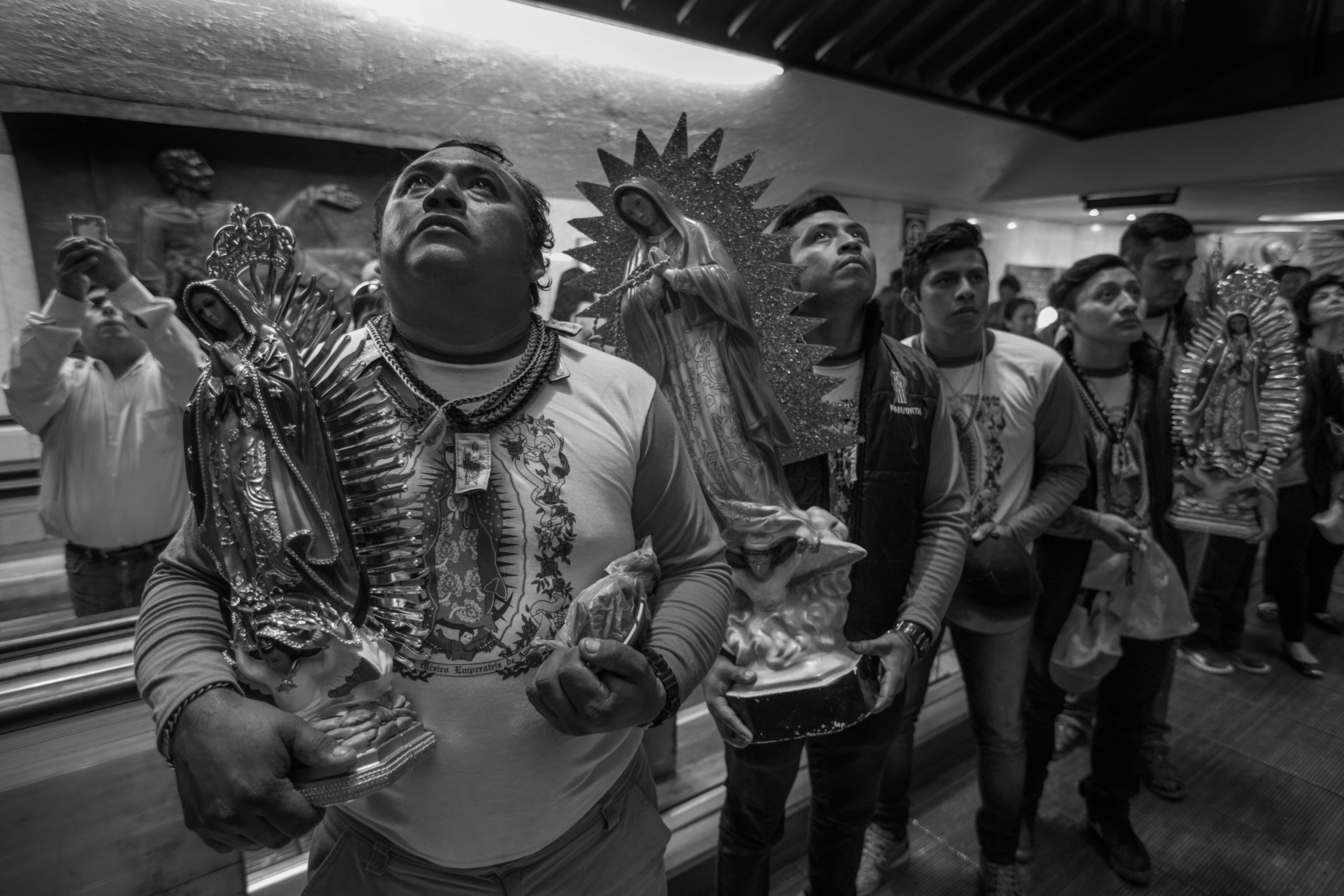 A group of people stand in a line holding statues and looking up