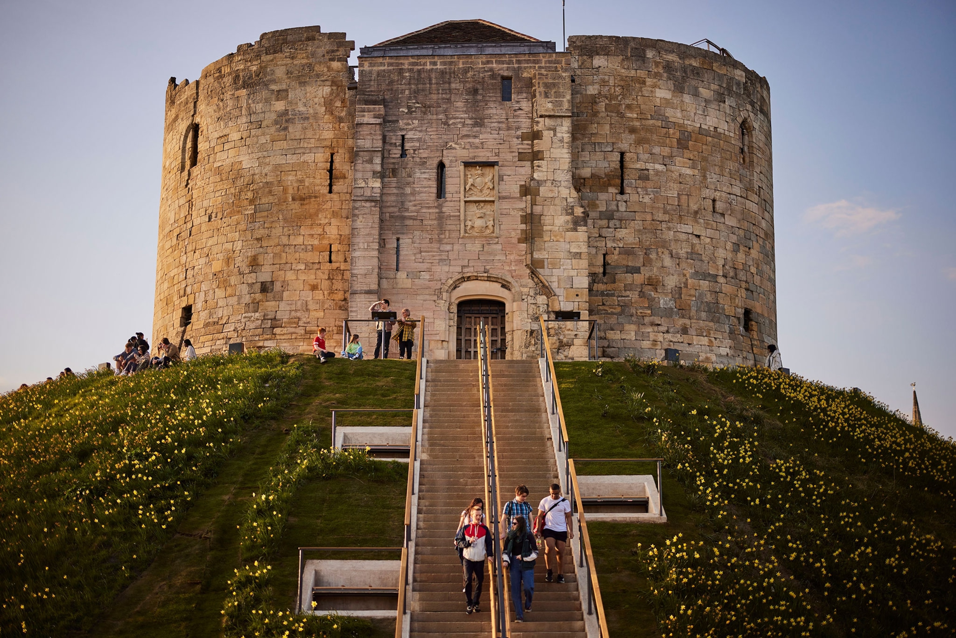 People walk down steps leading to a tower on a hill.