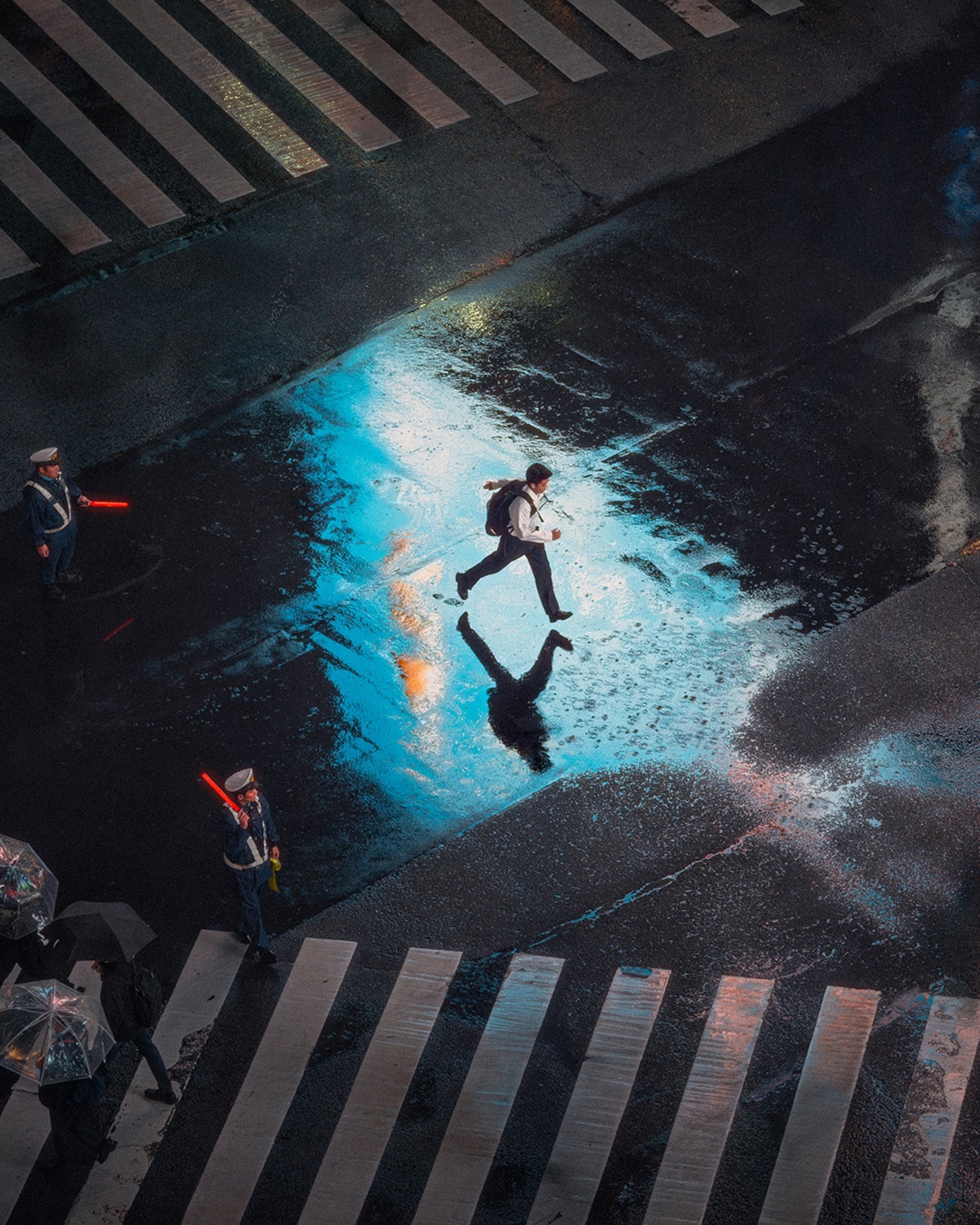 A person rushing across a street crossing in Tokyo in the rain.