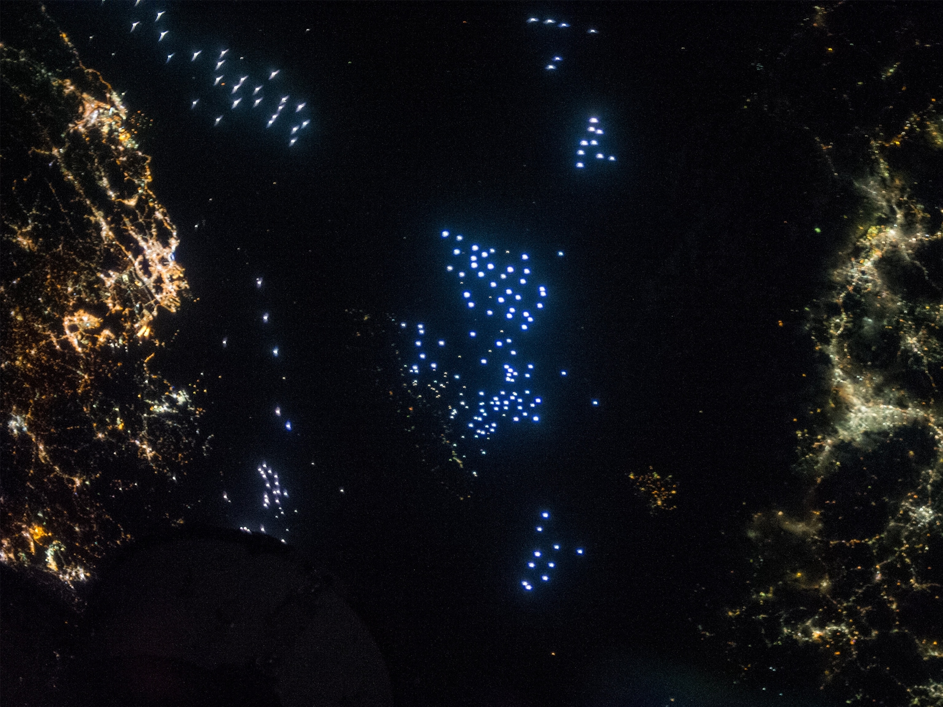 different colored lights coming from cities and fishing boats near Japan.