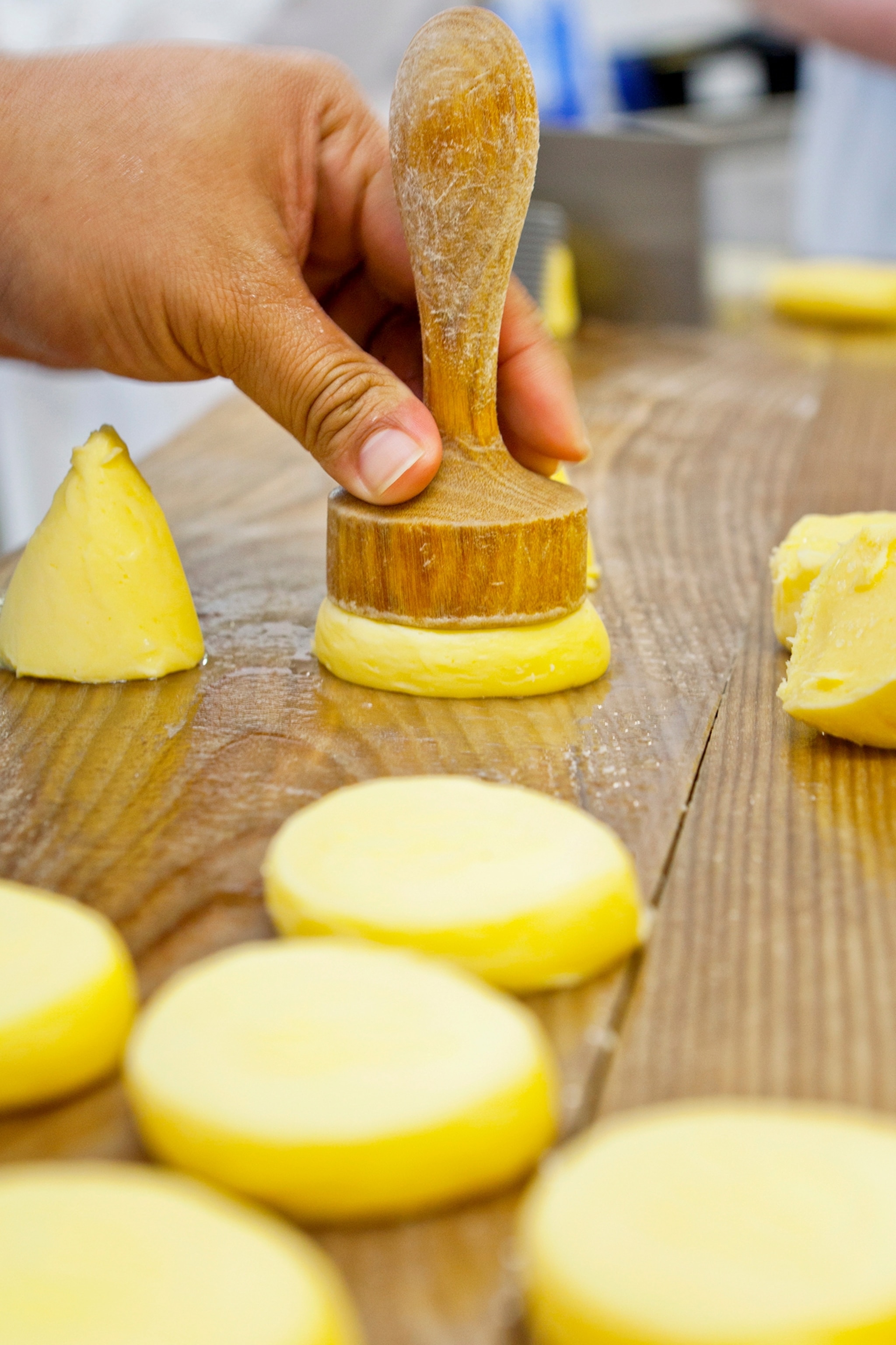 France, Brittany, St Malo, Europe, April 2014. Worker stamps round pieces of butter with wooden stamp, French butter maker Jean-Yves Bordier, food production, economy, manufactory, craft, travel