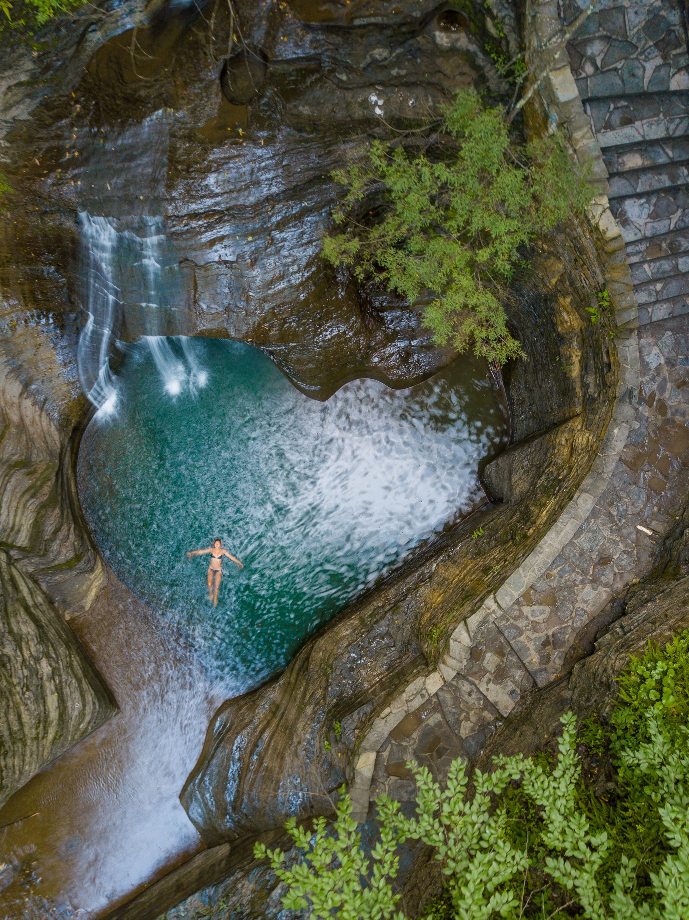 a girl swimming beneath a waterfall