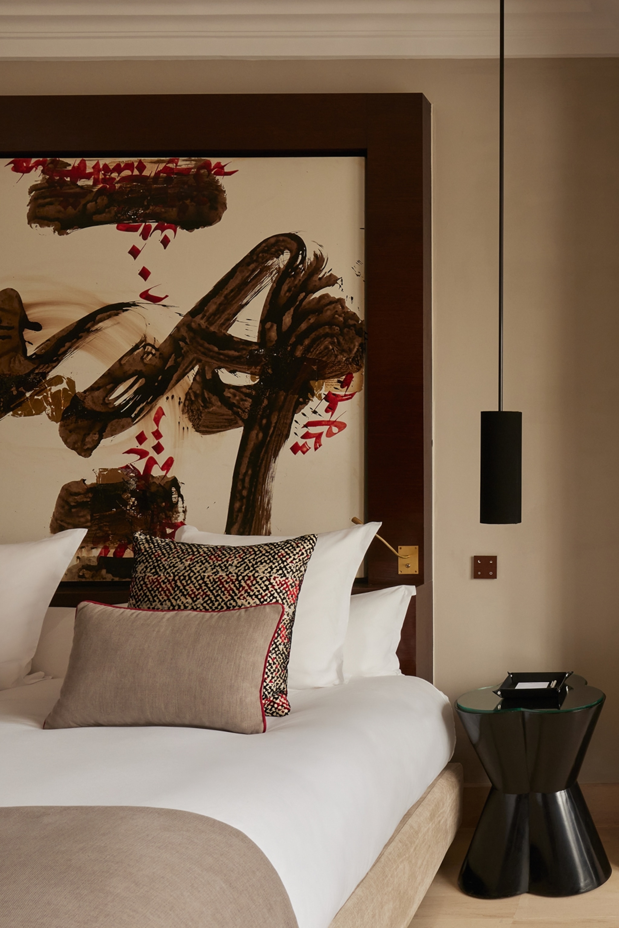 The interiors of a sleek, Japanese-style hotel room with grand kabuki brush strokes to the back of the bed.