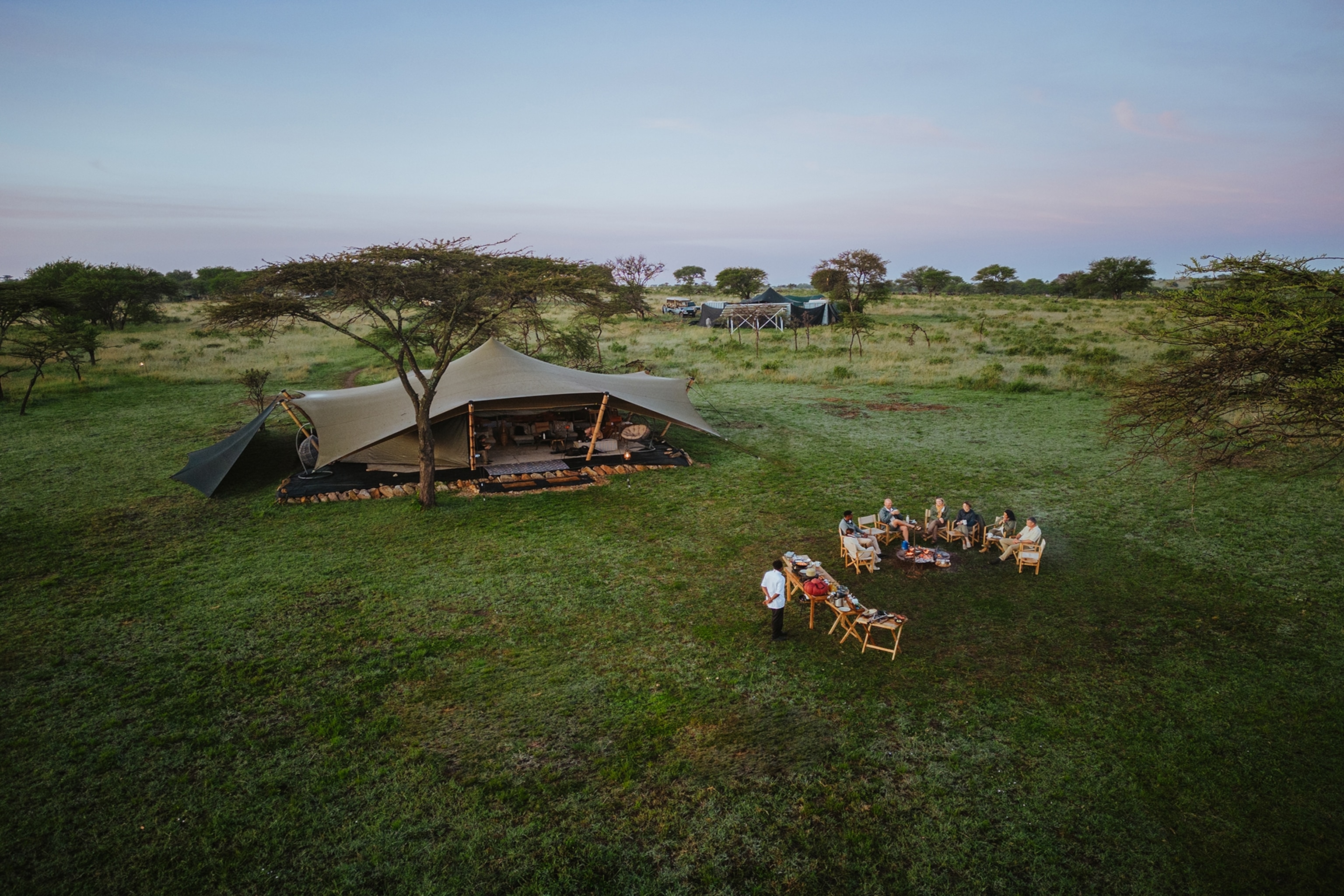 A group of guests at Wilderness Usawa Serengeti eat dinner outside their mobile safari camp in Serengeti National Park.