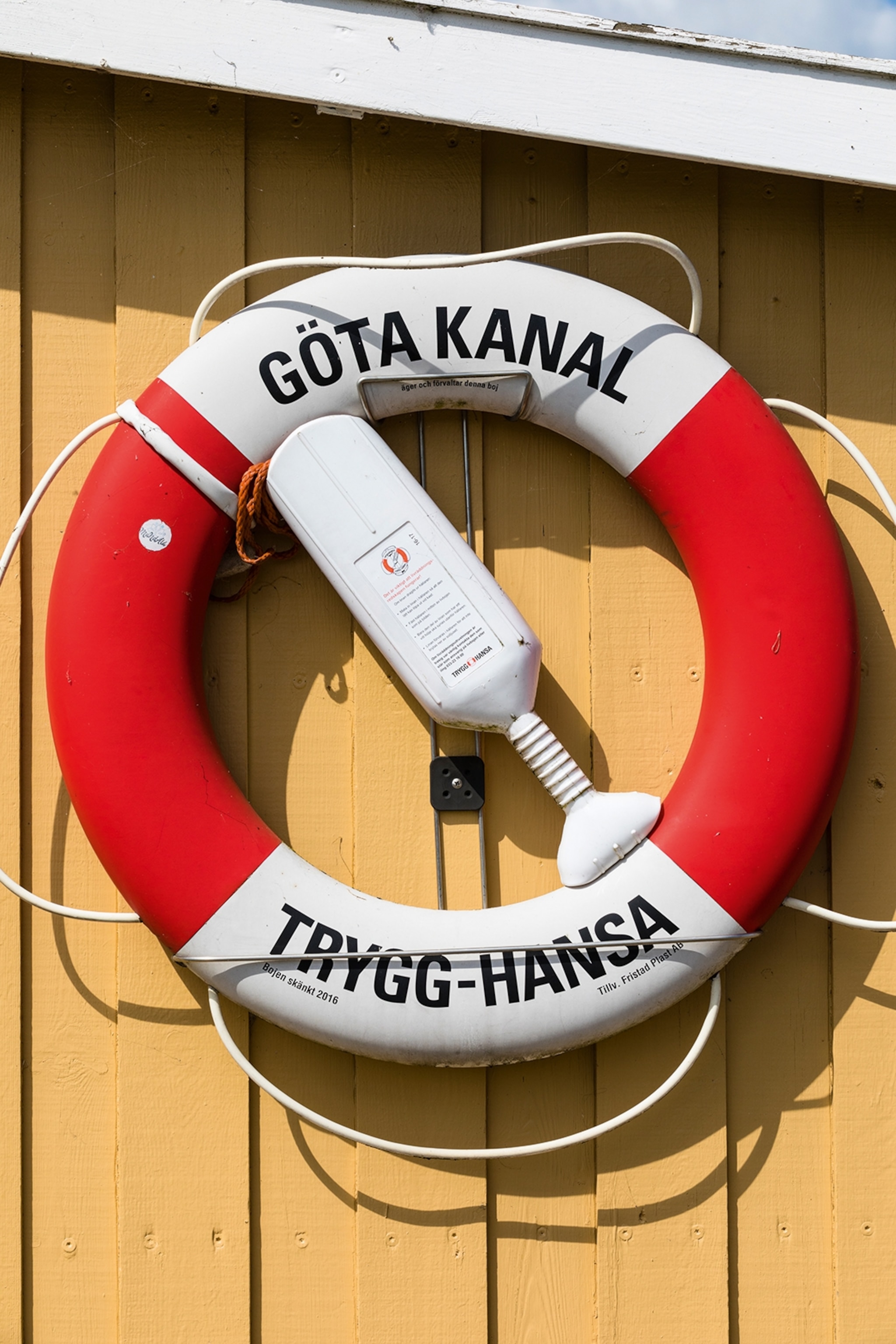 A swim ring hung on a wooden wall of a building.
