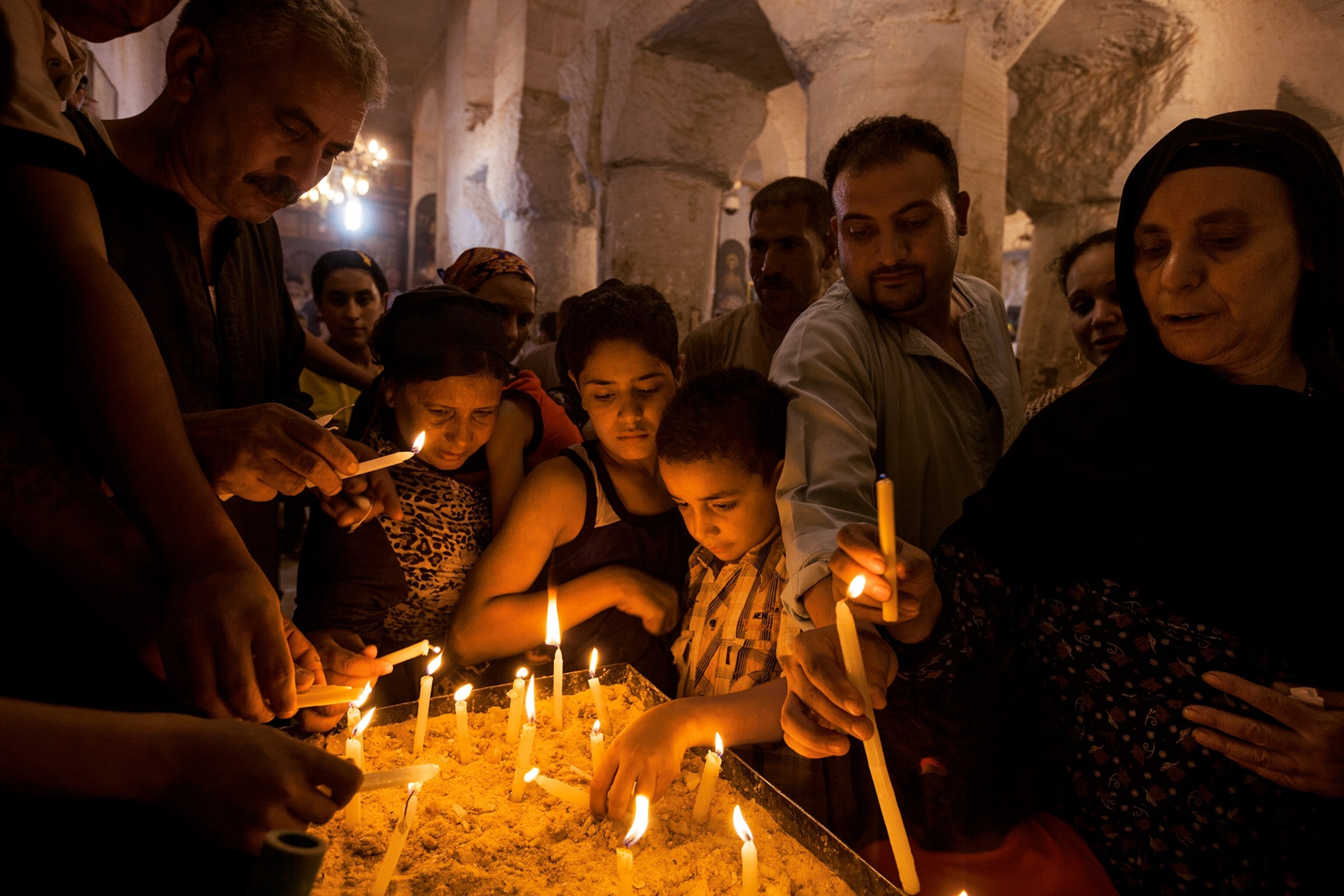 people lighting candles at the Deir al Adra monastery in Minya, Egypt, to honor the Holy Family's stay during their biblical flight to Egypt