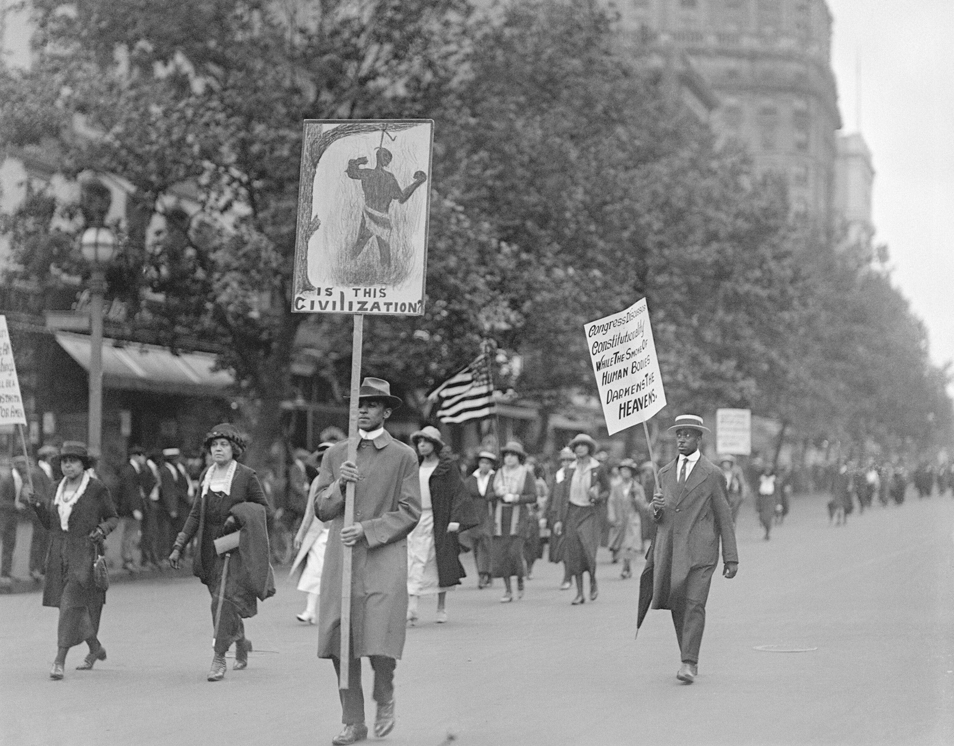 protesters walking down a street holding signs against lynching