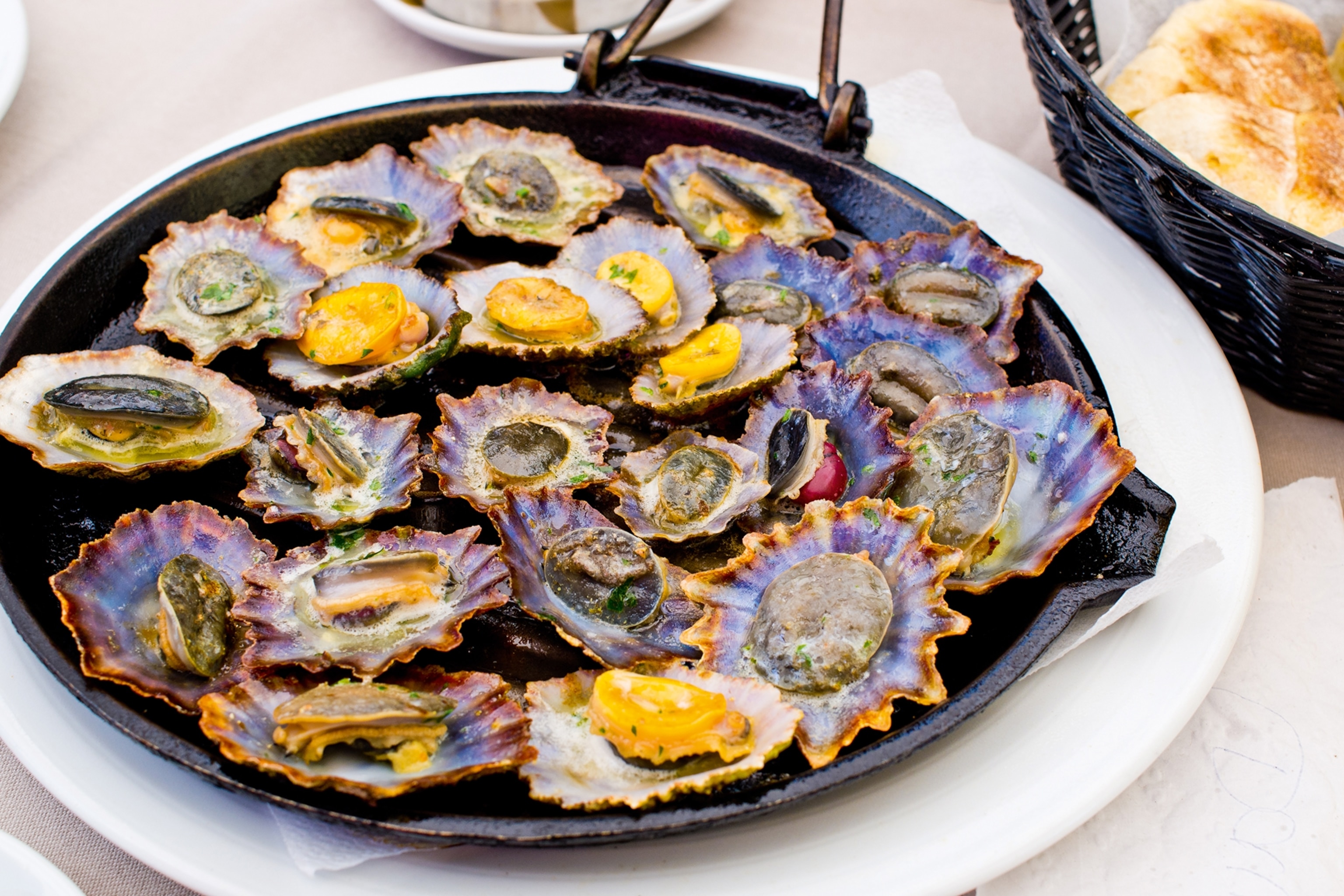 A plate of cooked limpets in an herby butter.