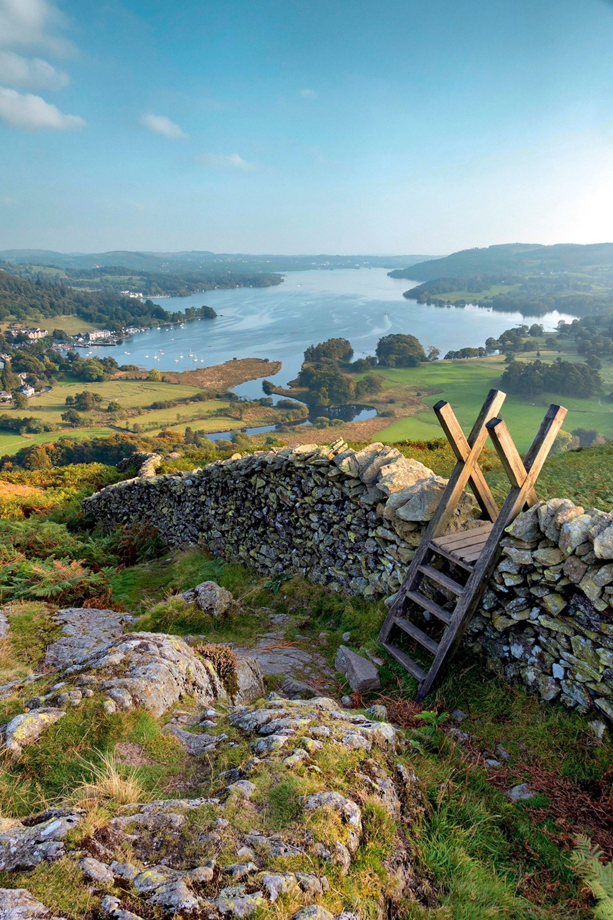View of Lake Windemere from hilltop with stone wall.