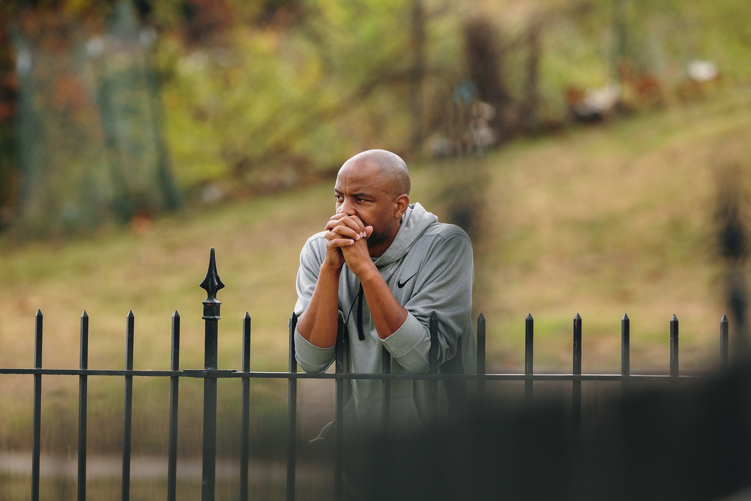 Man looking over a fence with his hands clasped in front of him