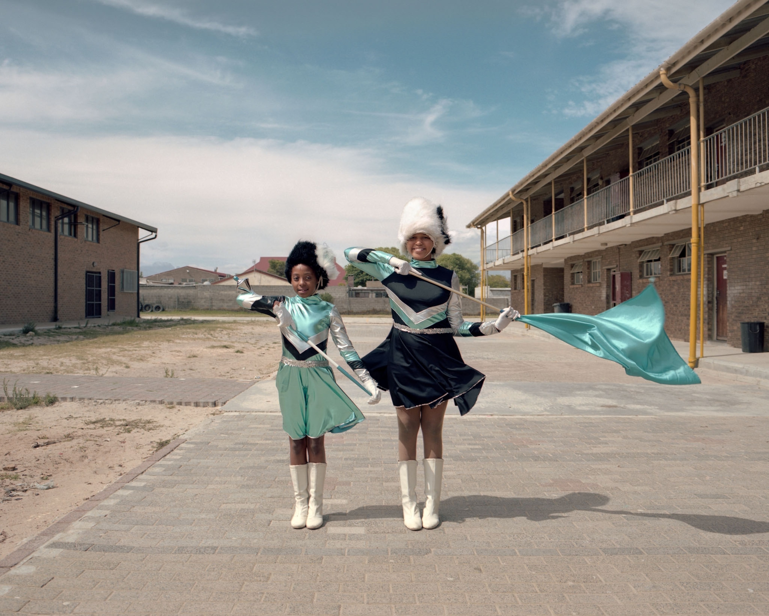 two young women holding flags in a vacant lot