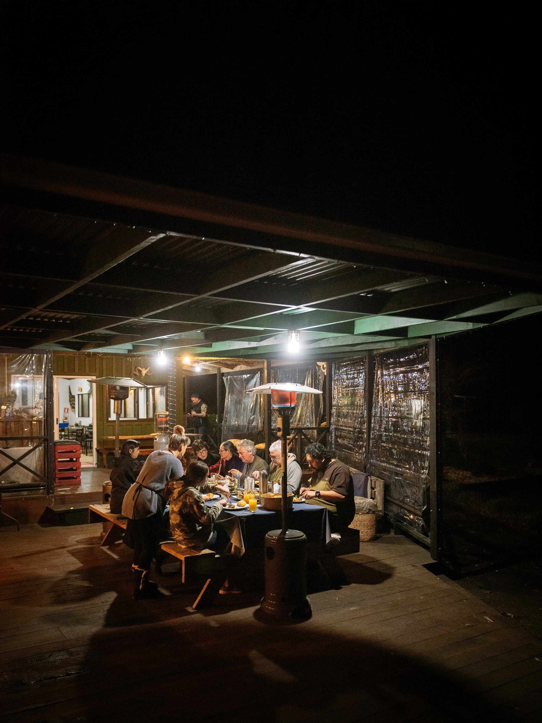 The whānau (family) and their guests sit down to dinner on the terrace.
