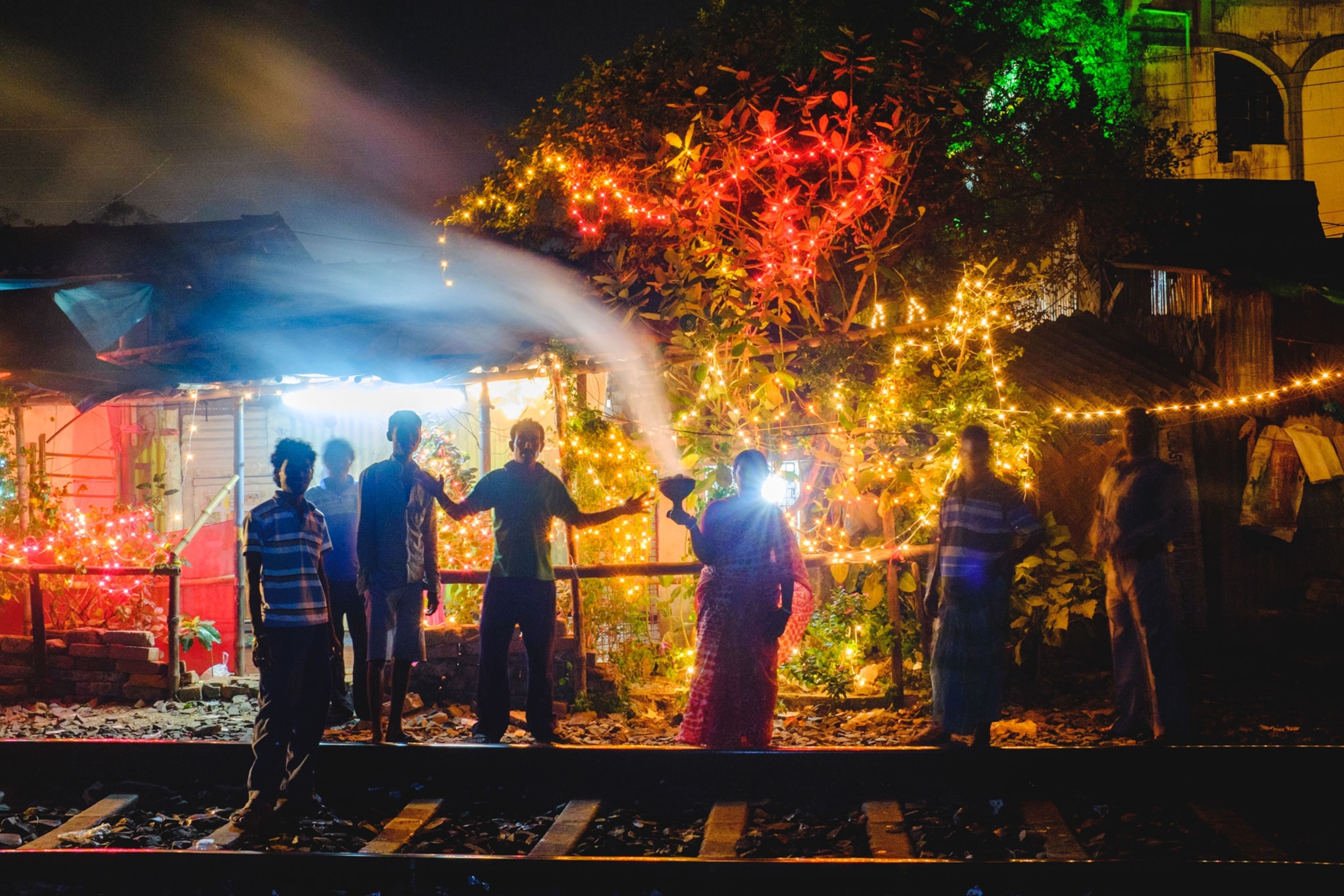 people standing in front of a makeshift temple by a railroad track